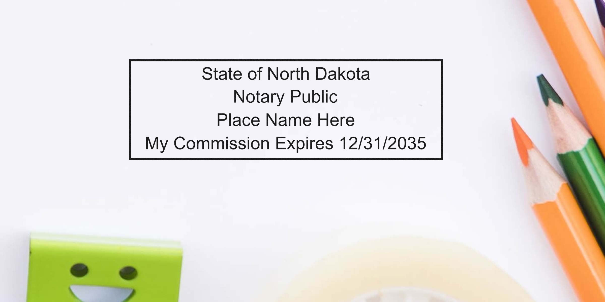 Rectangular North Dakota notary stamp sample reading "State of North Dakota Notary Public Place Name Here My Commission Expires 12/31/2035" with colored pencils and tape on white desk.