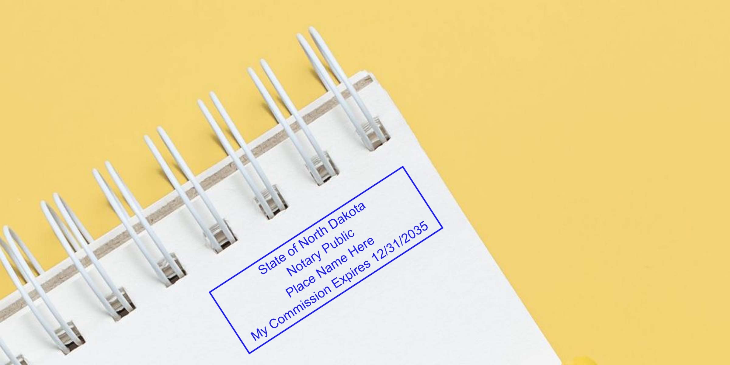Close-up of blue notary stamp imprint reading "State of North Dakota Notary Public Place Name Here My Commission Expires 12/31/2035" on white spiral notebook against yellow background