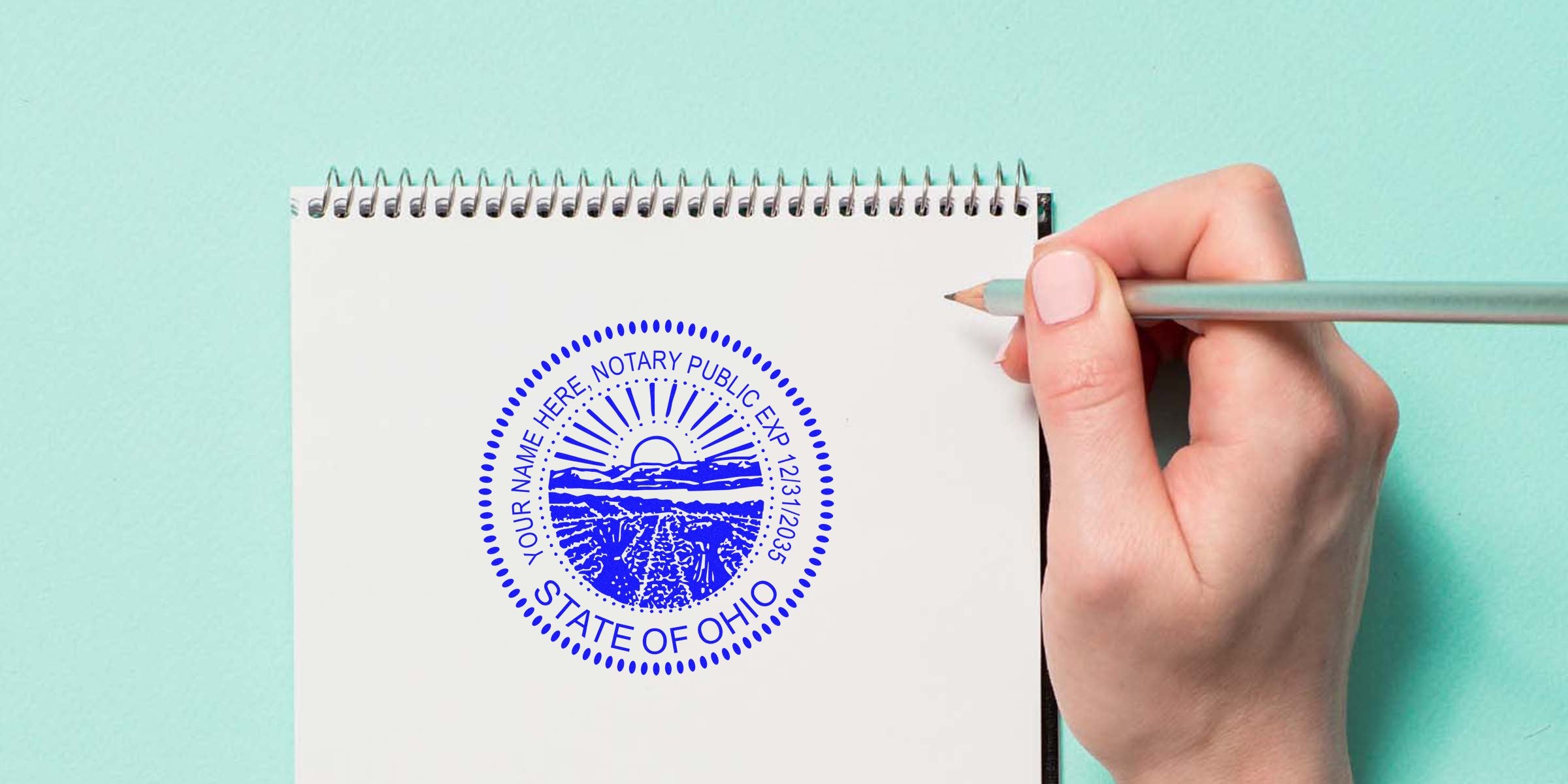 Close-up of blue State of Ohio notary public seal stamped on a white spiral notebook page, hand holding a mint pencil beside the stamp on a pastel teal background — Ohio notary seal, notary stamp, notebook, pencil.
