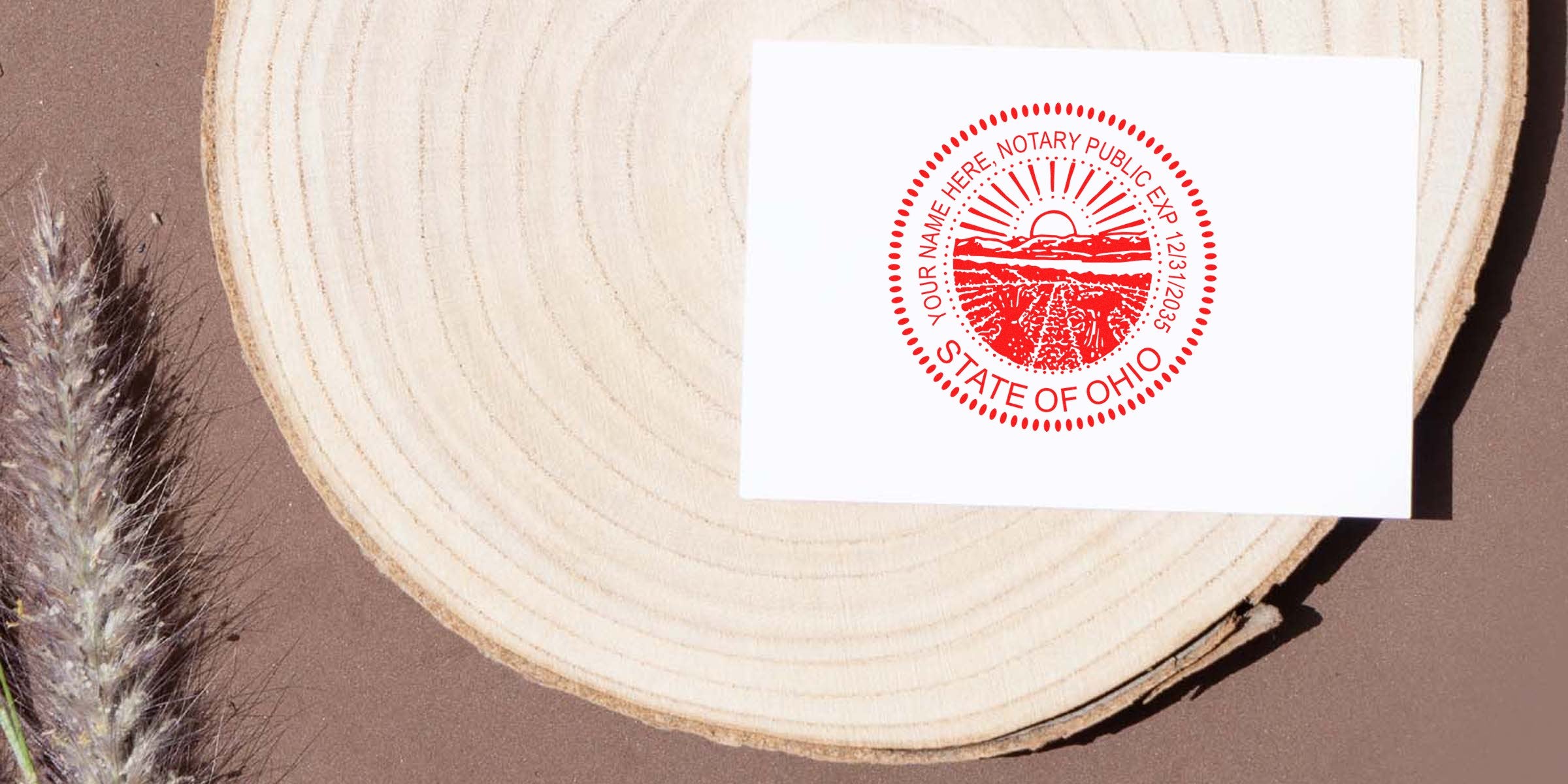White card with red State of Ohio notary public seal placed on a round wood slice on a brown background with dried grass.