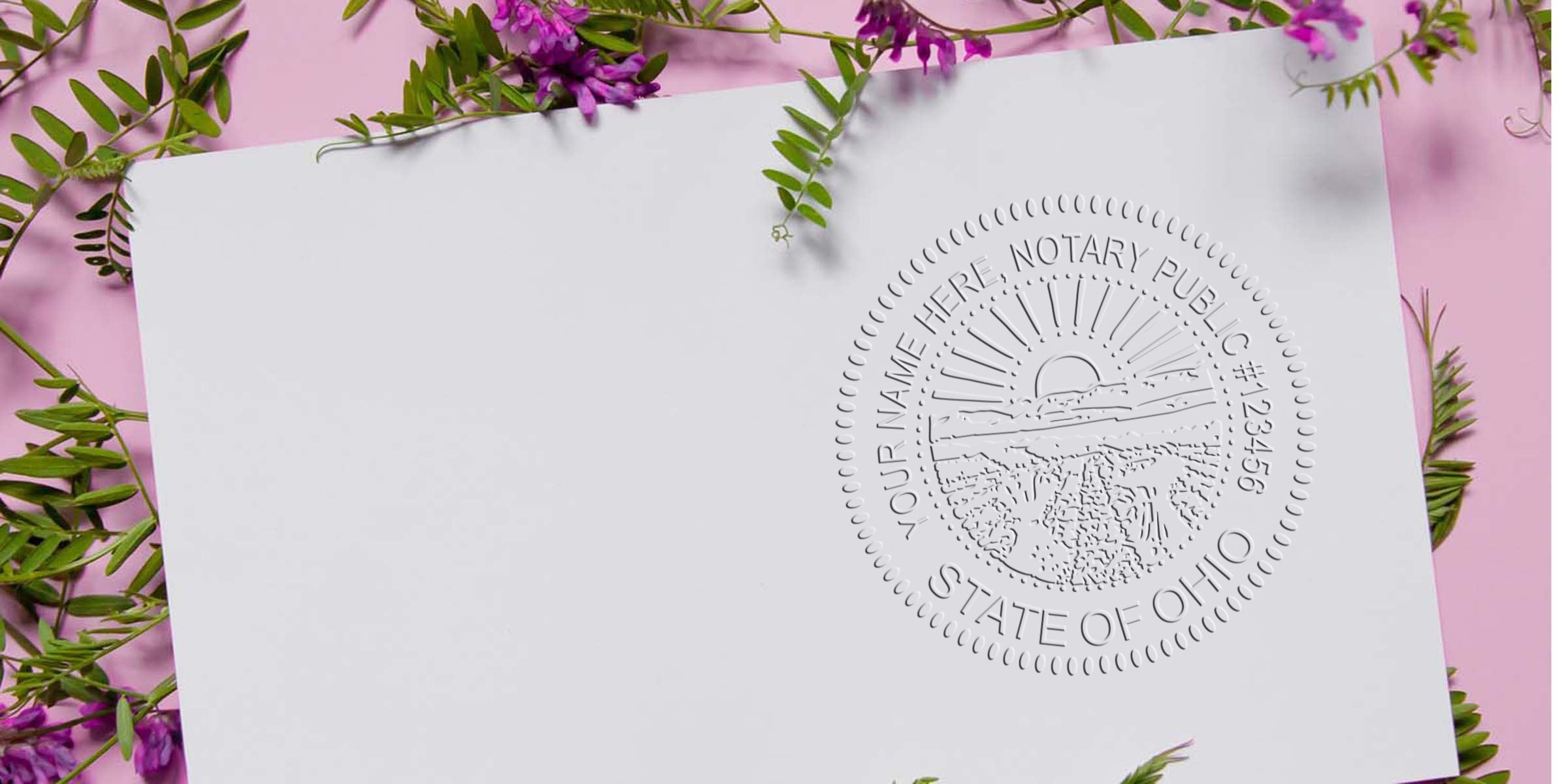 Embossed State of Ohio notary public seal on white paper, surrounded by pink backdrop and green leaves with purple flowers, close-up texture