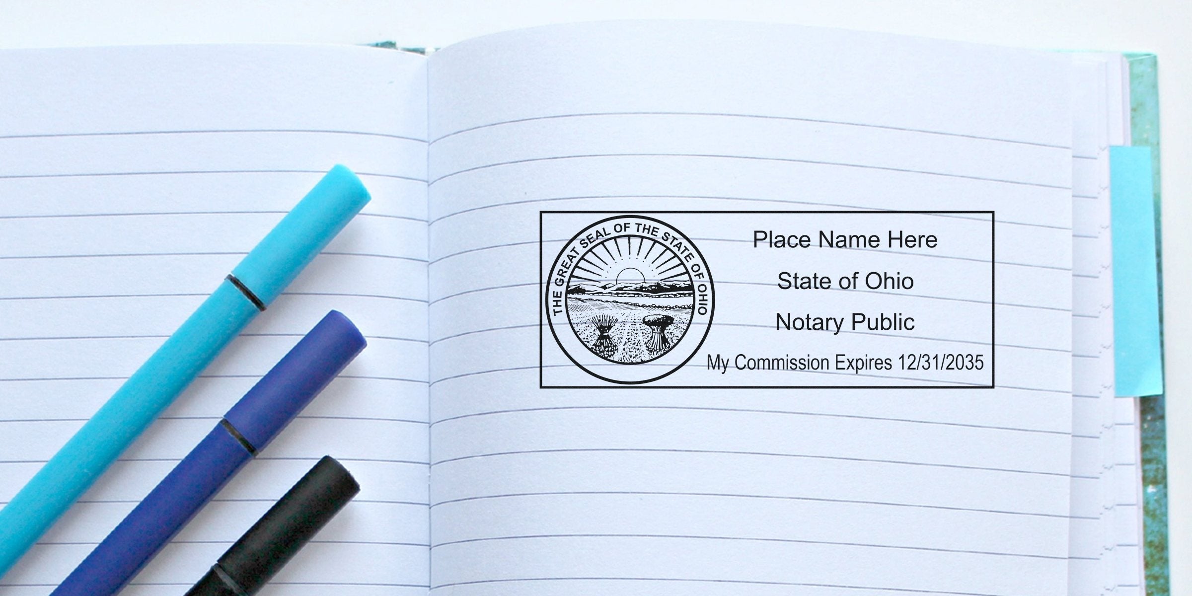 Open lined notebook with three colored pens and an Ohio notary public stamp imprint showing state seal and commission expiration date, stationery and notary concept for legal documents and office use