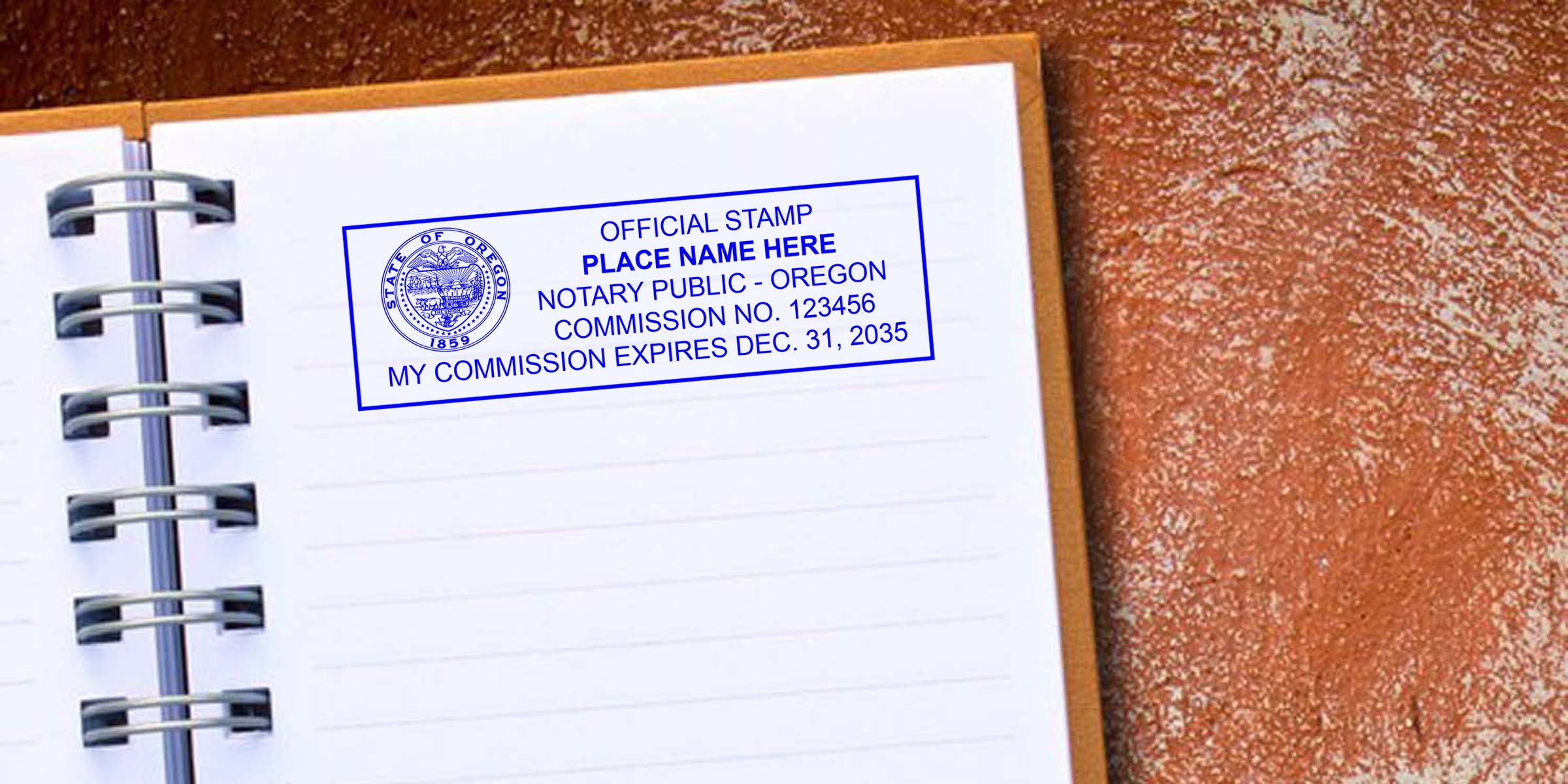 Open spiral notebook on a textured brown surface with a blue Oregon notary public stamp sample on a lined page showing commission number and expiration date.