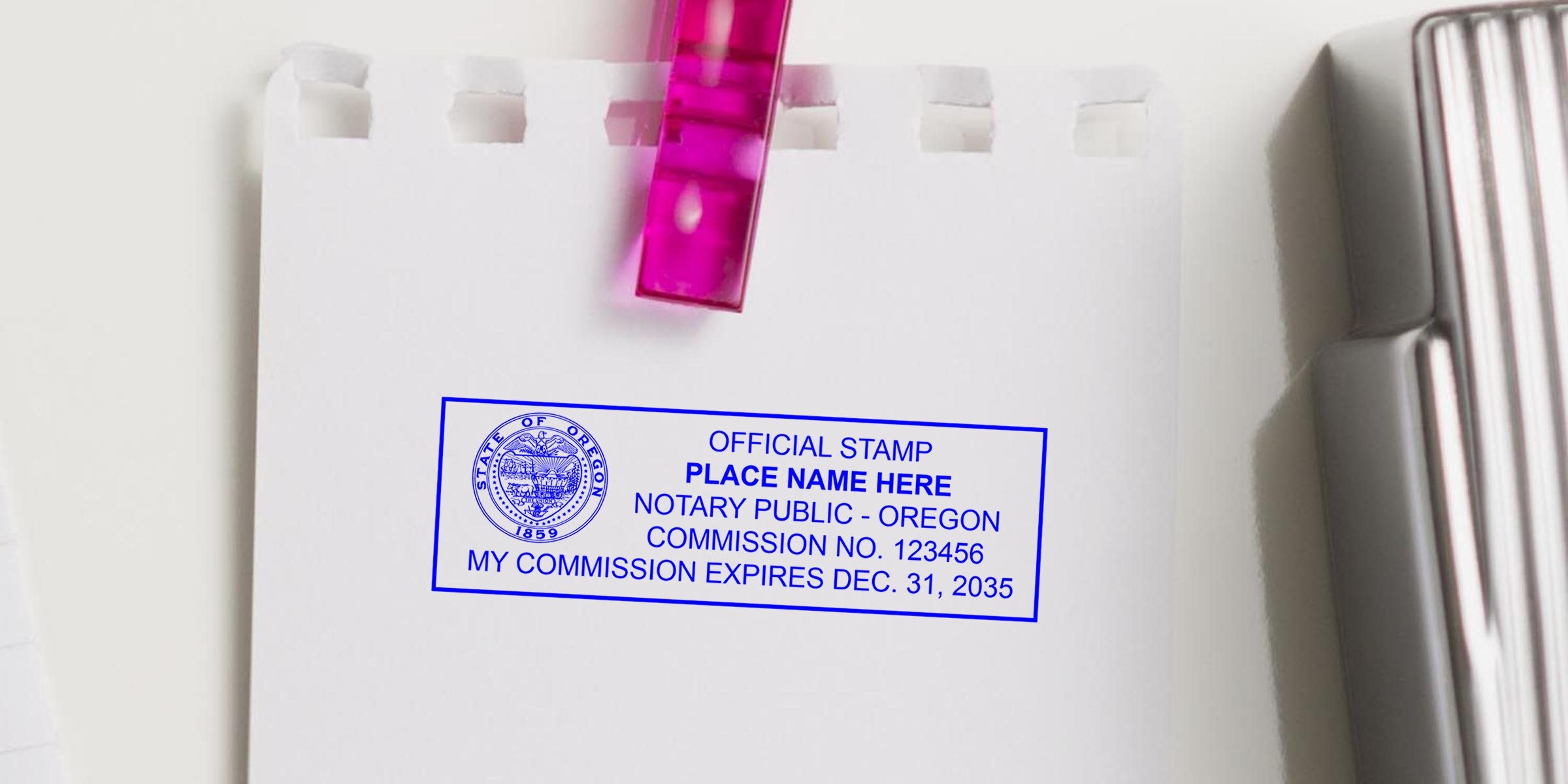 Blue Oregon notary public stamp on white torn notebook page clipped with pink binder clip, showing commission number and expiration date.