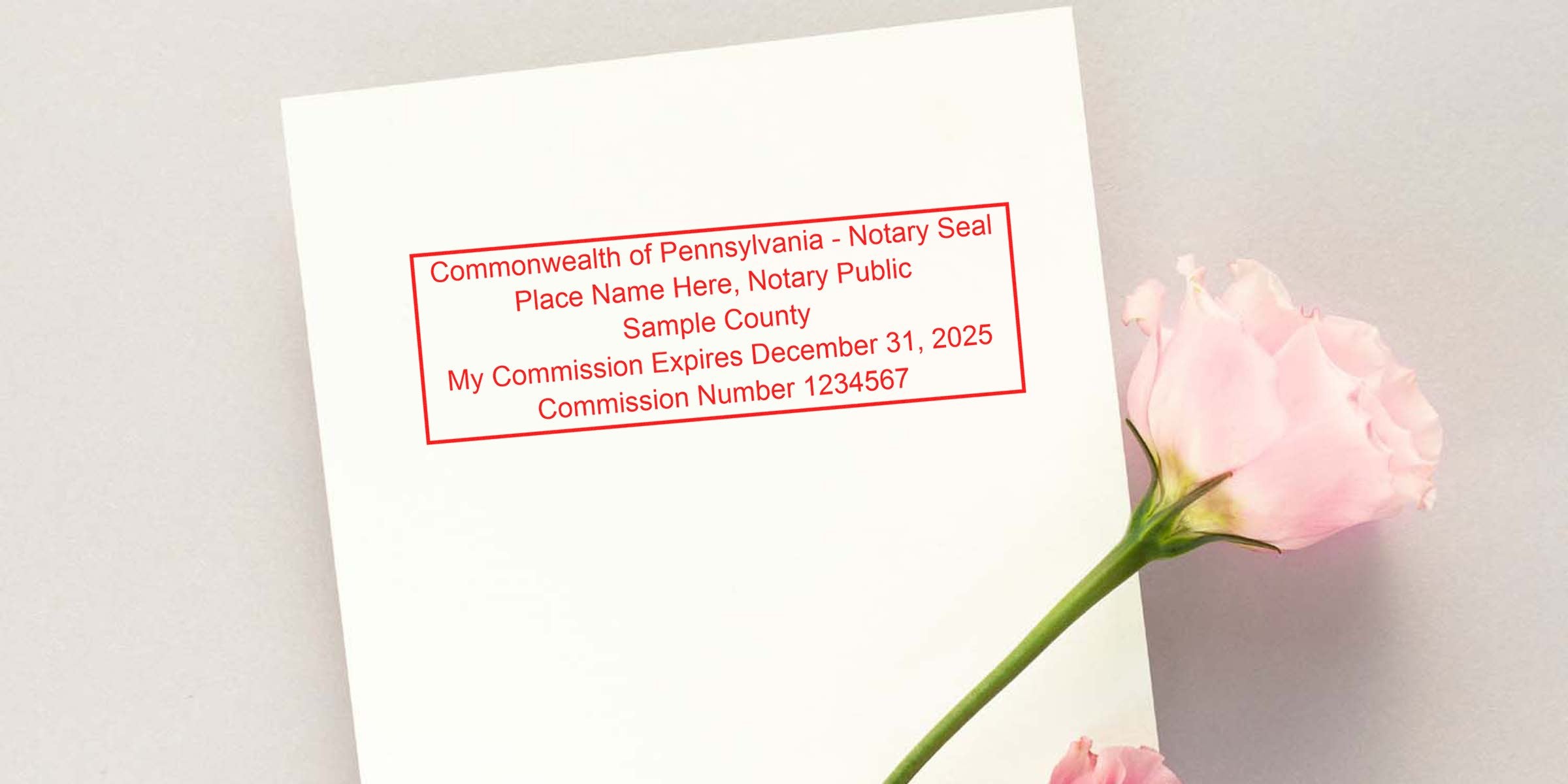 Red Pennsylvania notary seal sample in red ink on white paper showing commission info and number, styled with a pink rose on a light background