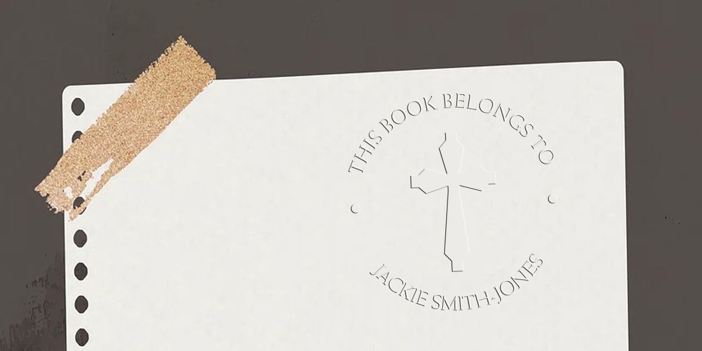 A notebook page with a circular stamp reading “This Book Belongs To” and a cross logo, with the name “Jacquie Smith-Jones” around the circle.
