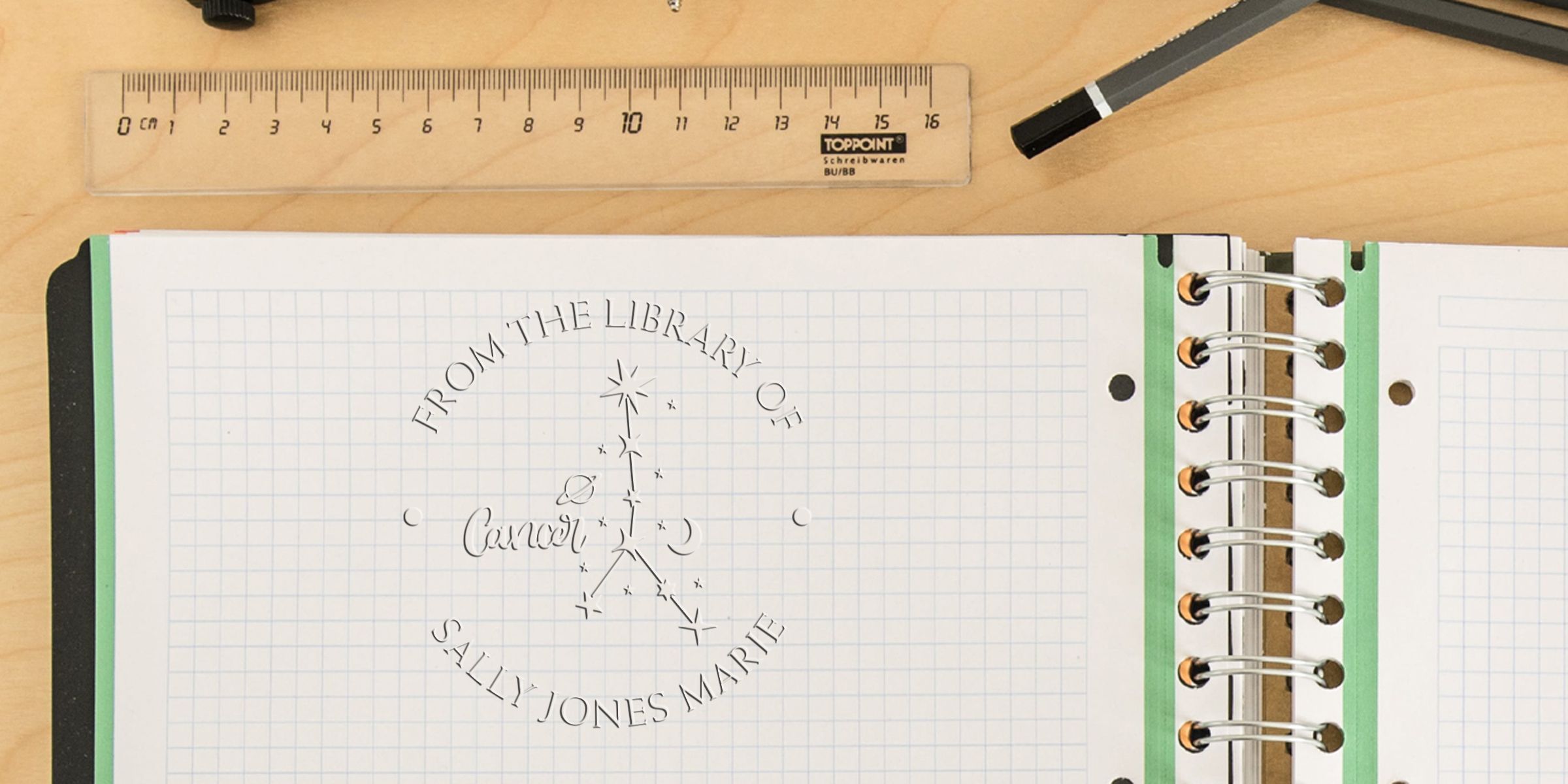 Stamp reading “FROM THE LIBRARY OF” in a circle with the name “SALLY JONES MARE” beneath, on a graph-paper notebook with a ruler and pencil nearby.