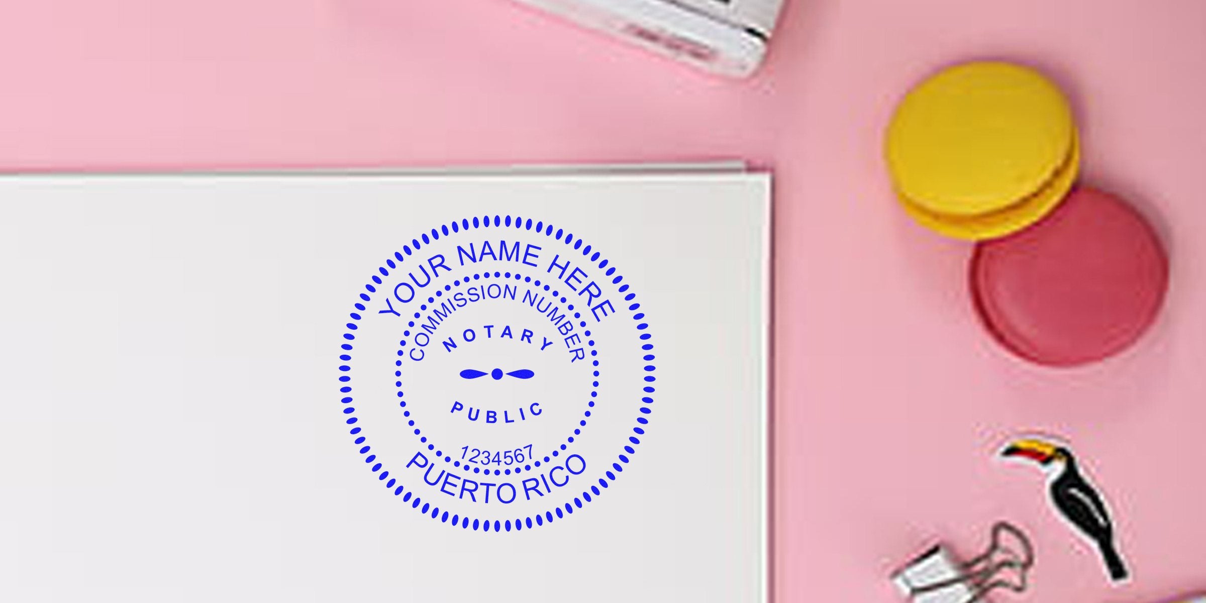 Flatlay of blue circular notary public stamp mockup reading "Puerto Rico" on white paper, on a pink desk with macarons and binder clip.