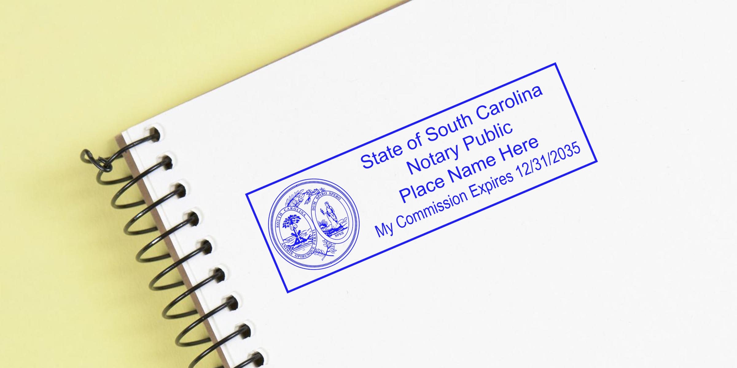 Blue State of South Carolina notary public stamp imprint on a white spiral notebook page against a yellow background, showing a circular seal, placeholder name text and commission expiration date 12/31/2035.