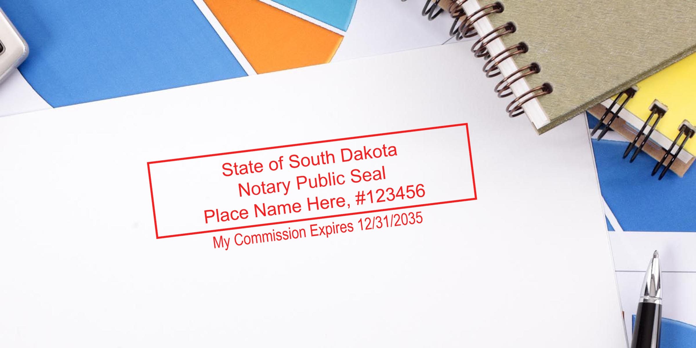 Red rectangular notary public seal stamp on white paper reading "State of South Dakota Notary Public Seal Place Name Here #123456 My Commission Expires 12/31/2035" with notebooks and pen nearby
