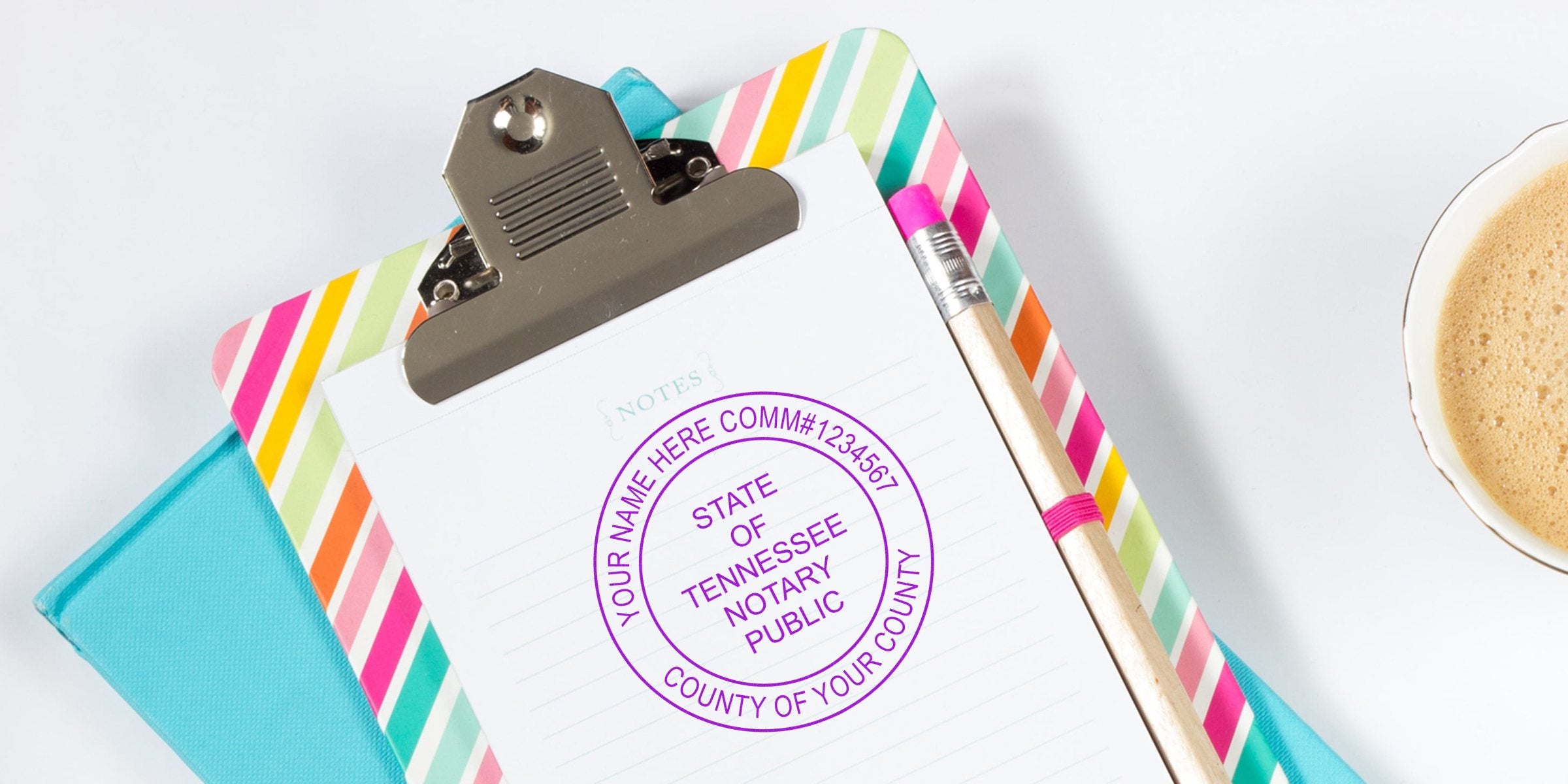 Top-down shot of a colorful striped clipboard with lined notepad stamped "State of Tennessee Notary Public," wooden pencil and cup of coffee — notary stamp workspace photo