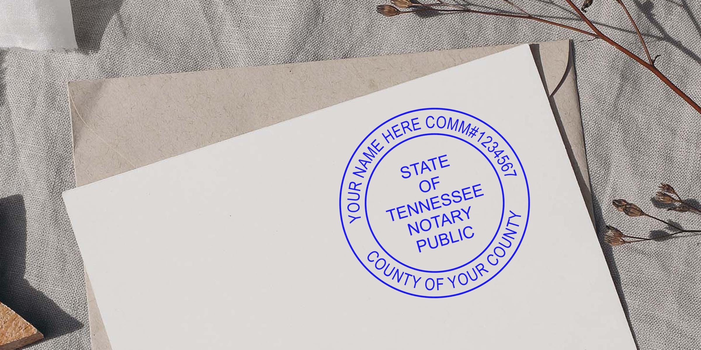 Blue circular Tennessee notary public seal stamped on white card over kraft envelope, textured linen background and dried flowers nearby
