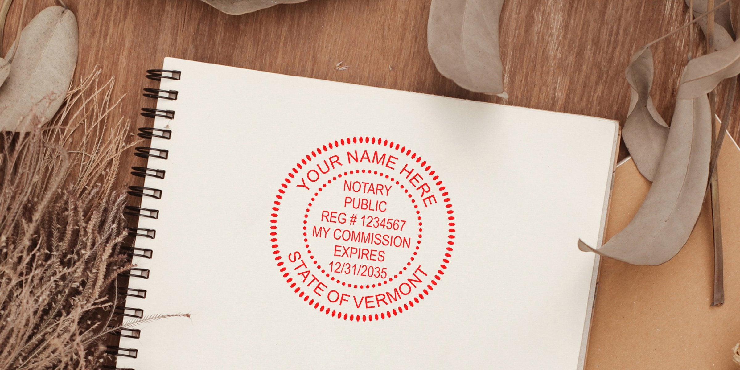 Spiral notebook page with a red circular notary stamp mockup reading "Your Name Here, Notary Public, Reg #1234567, My Commission Expires 12/31/2035, State of Vermont" surrounded by dried leaves on a wooden surface