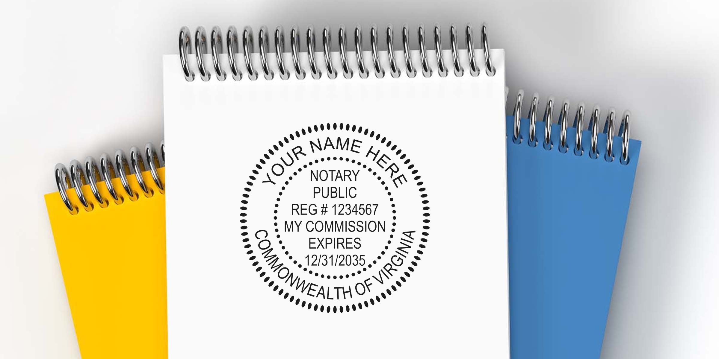 Notary public round stamp mockup on white spiral notepad with yellow and blue notebooks behind, "Commonwealth of Virginia" placeholder name and commission expiry info.