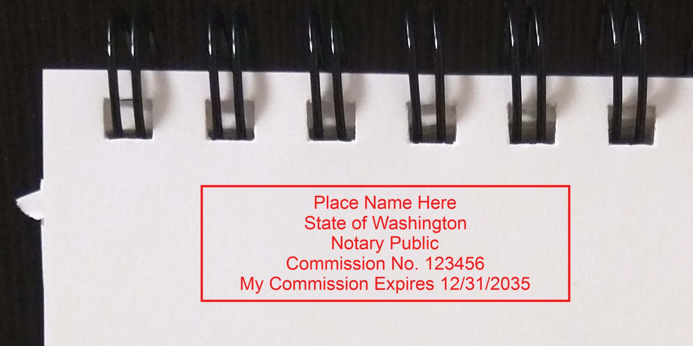 Close-up of a spiral-bound notebook top showing a red notary public stamp reading "Place Name Here, State of Washington, Notary Public, Commission No. 123456, My Commission Expires 12/31/2035."