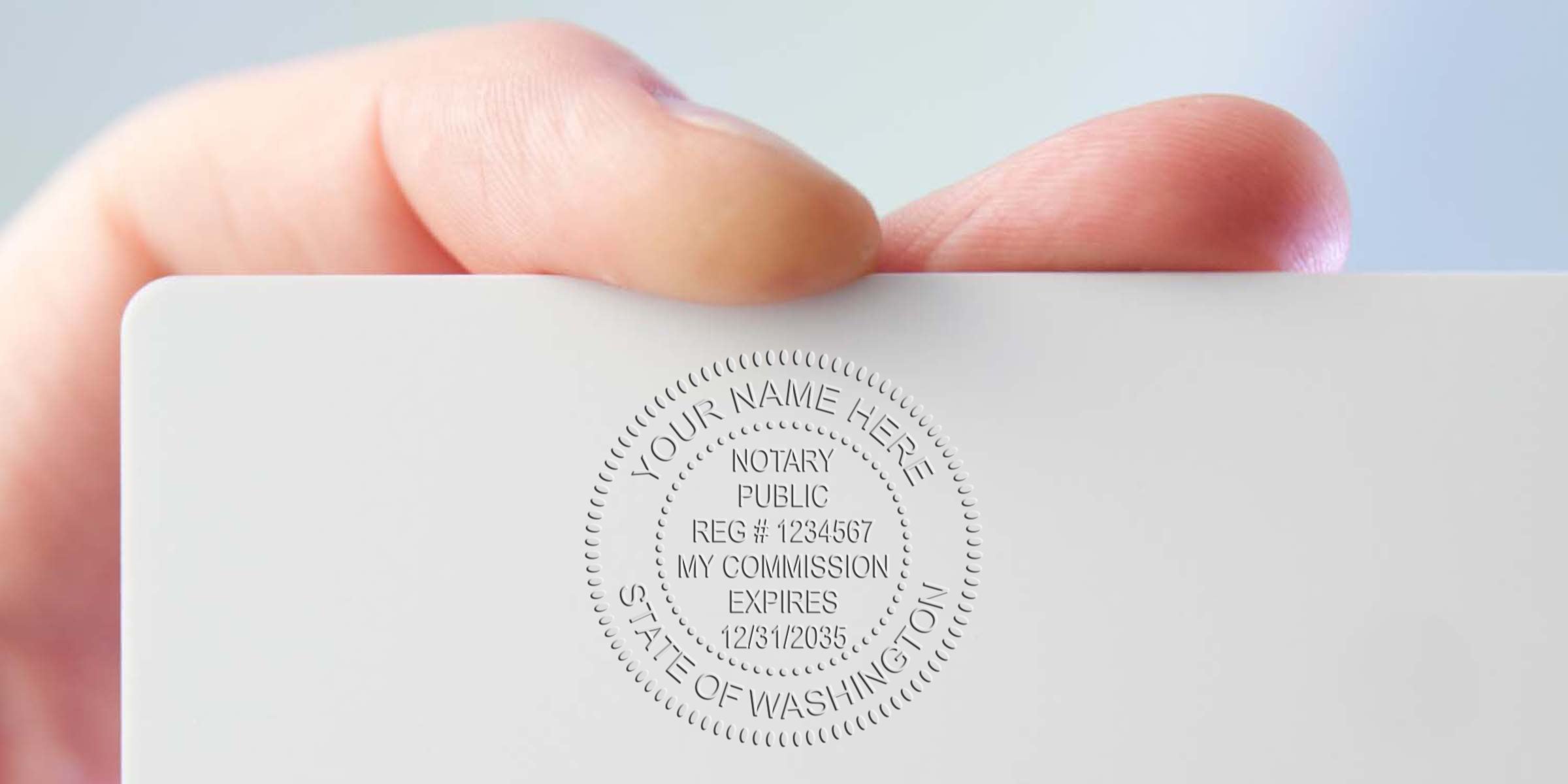 Close-up of hand holding a white card embossed with a Notary Public seal reading "State of Washington," showing registration number and commission expiry details.