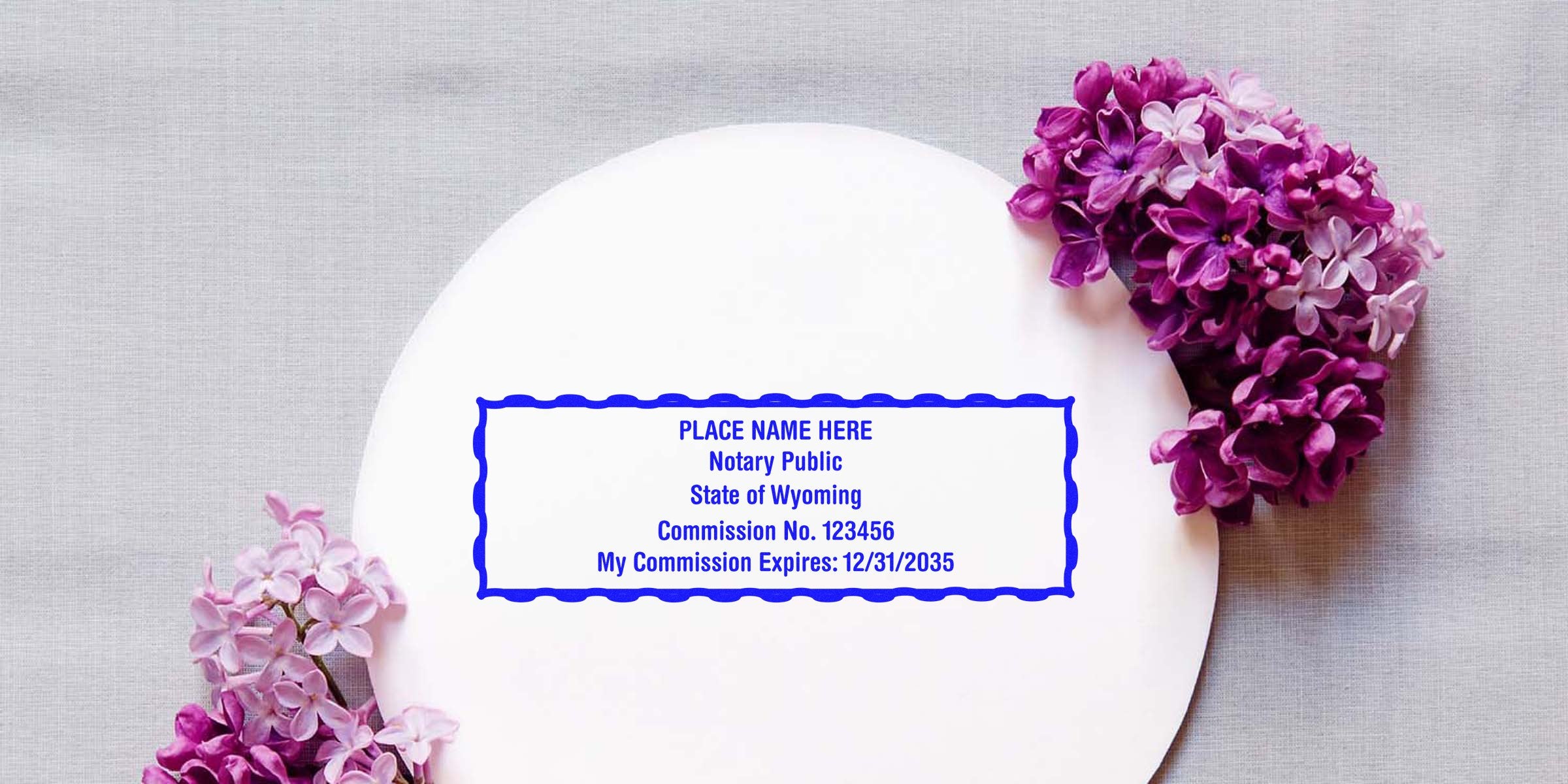 Blue rectangular notary stamp template on white circular background reading "Notary Public State of Wyoming" with placeholder name, commission details, and purple lilac flowers.