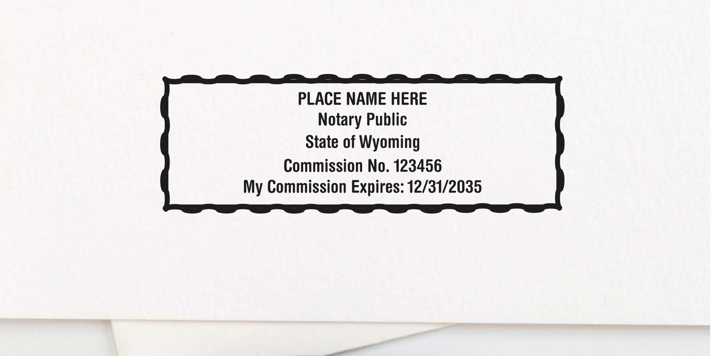 Rectangular wavy-border notary stamp mockup reading "PLACE NAME HERE Notary Public State of Wyoming Commission No. 123456 My Commission Expires: 12/31/2035" on white paper