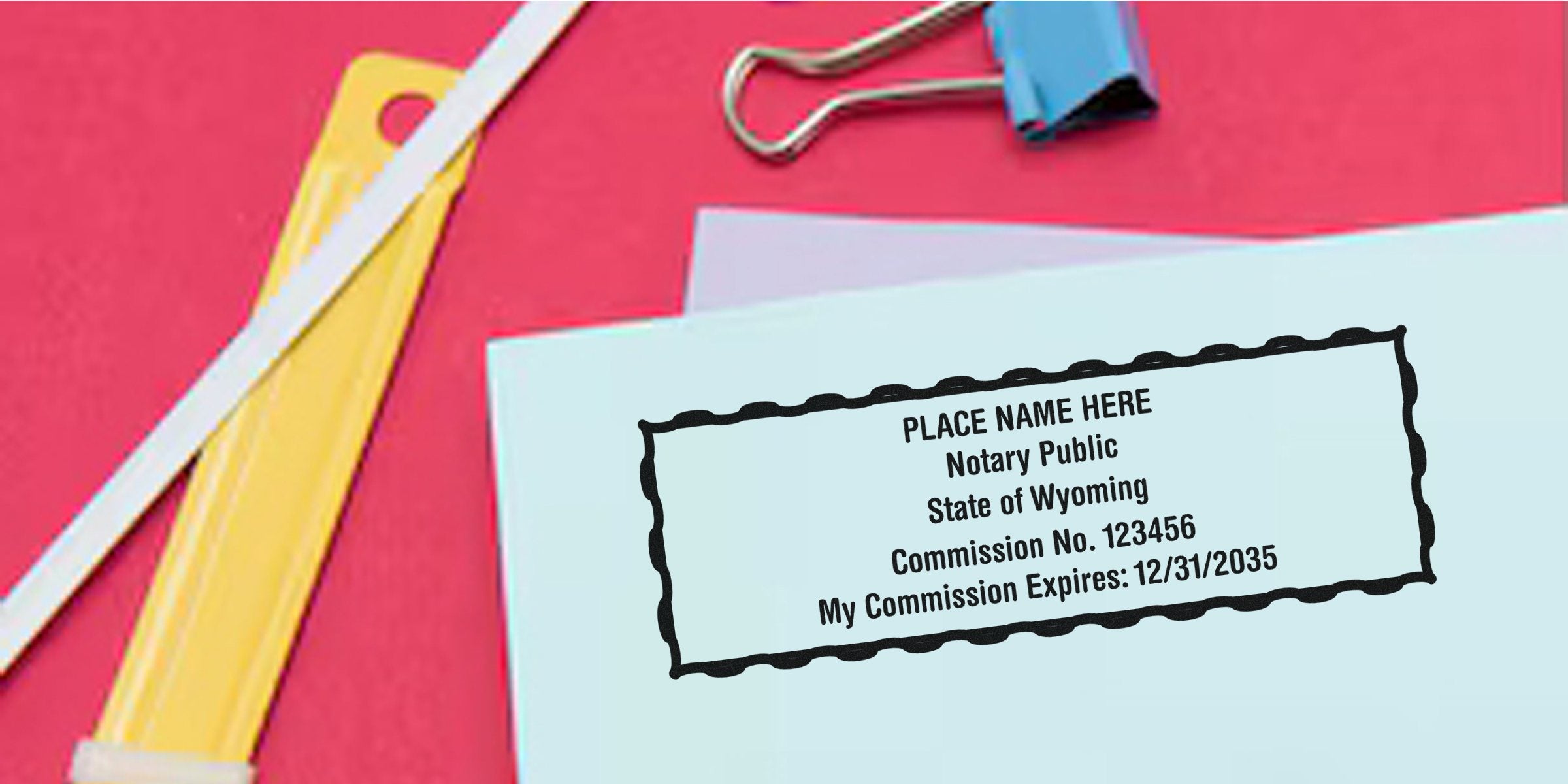 Light blue document with a black notary public stamp mockup reading "Notary Public, State of Wyoming, Commission No. 123456" beside colorful office supplies.