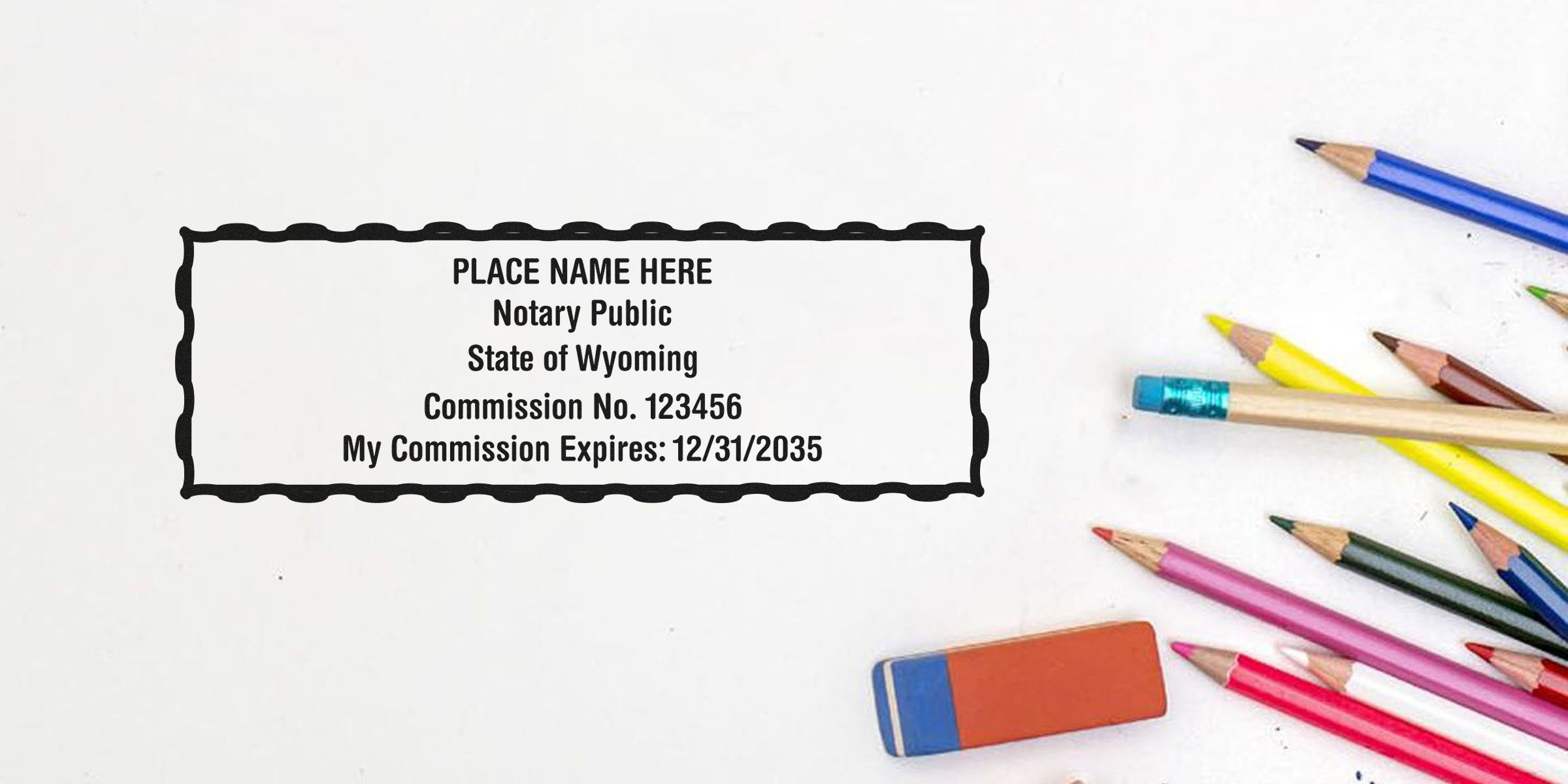 Blank Wyoming notary stamp template showing sample name, commission number and expiration date centered on paper, surrounded by colored pencils and an eraser — customizable notary stamp mockup