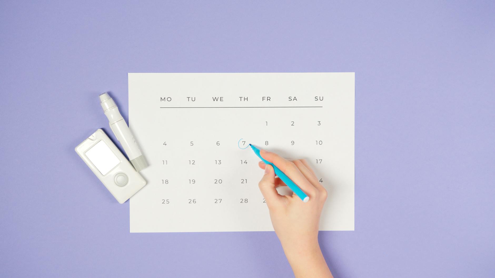 Hand circling the 7 on a minimal monthly calendar with a blue pen, placed beside a white glucose meter and insulin pen on a lavender background — diabetes appointment or medication reminder.