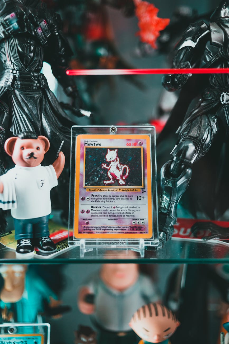 Close-up of vintage Mewtwo Pokémon trading card in a protective case displayed among collectible action figures and toys on a glass shelf.