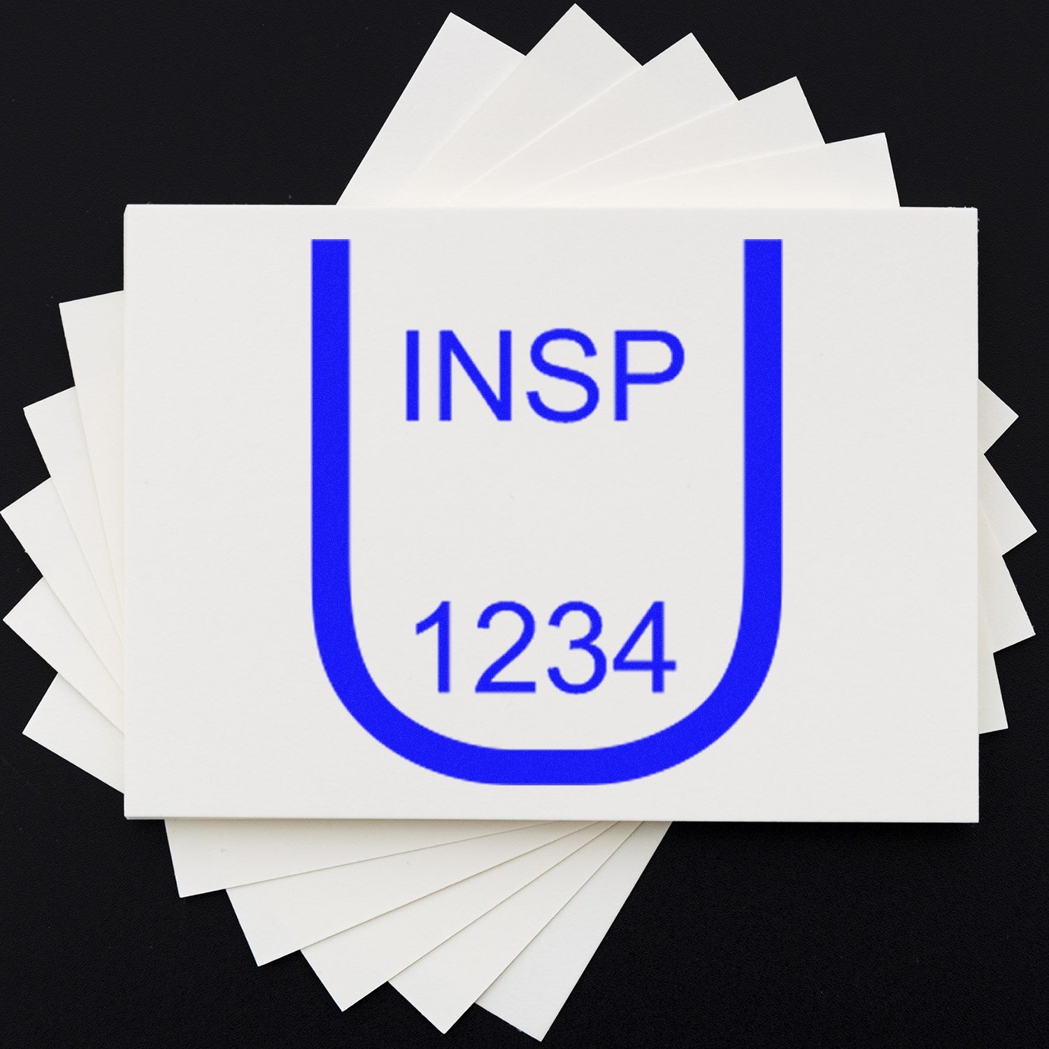 Blue INSP 1234 stamp and seal on stacked white cards against a black background.