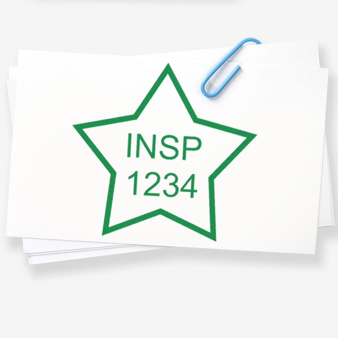 Green star inspection stamp seal with INSP 1234 on stacked white papers, clipped with a blue paperclip.
