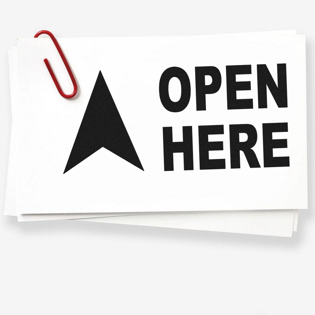 Slim Pre-Inked Arrow Open Here Stamp featuring a bold black arrow and OPEN HERE text on white paper, secured with a red paperclip. Ideal for clear, precise labeling.