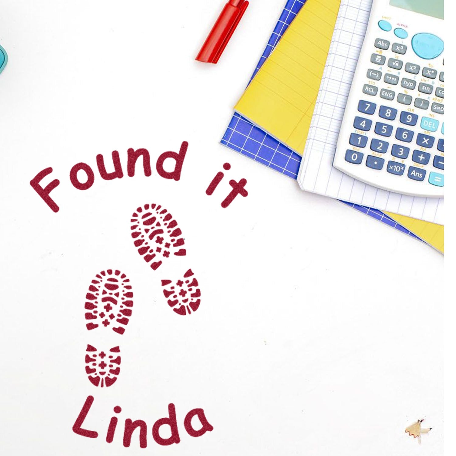 Custom red stamp seal with footprints, Found it and Linda, beside a calculator and colorful notebooks.
