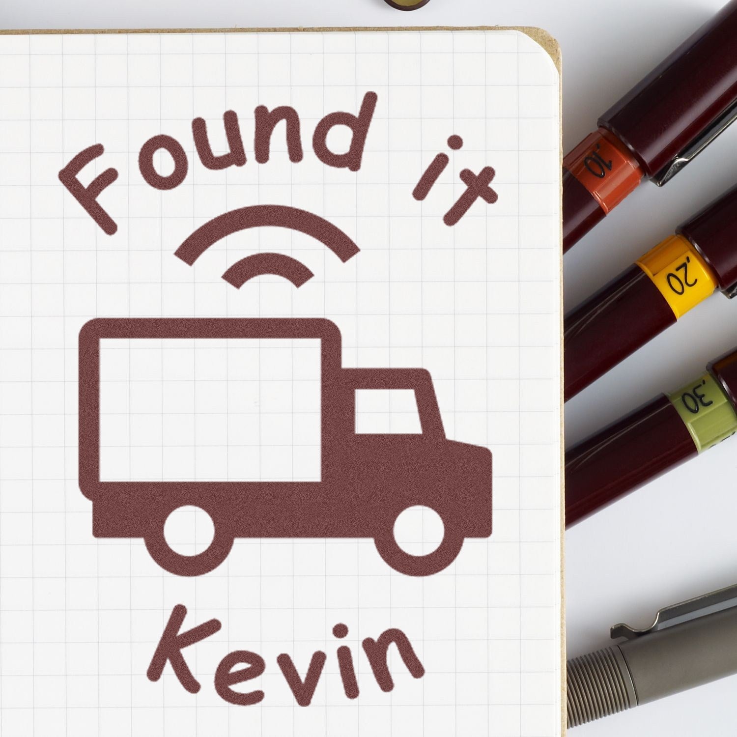 Brown Found it delivery truck stamp on grid paper, with burgundy, orange, yellow, and green seal markers beside it.