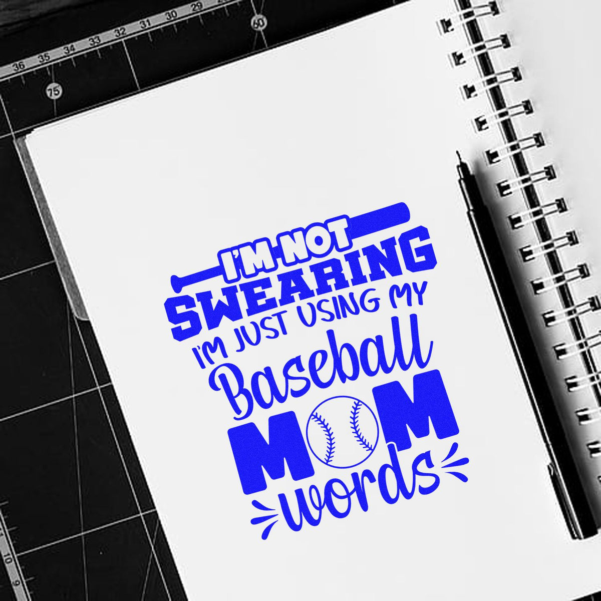 Blue custom stamp and seal design on a white notebook reads Im not swearing, Im just using my baseball mom words.