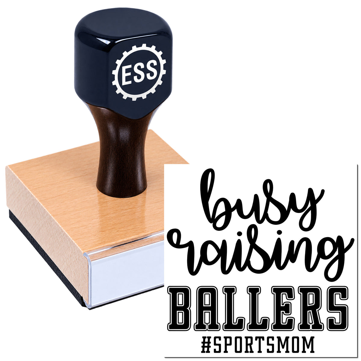 Navy rubber stamp with ESS gear logo on a wooden block, showing "busy raising BALLERS" and #SPORTSMOM in black.