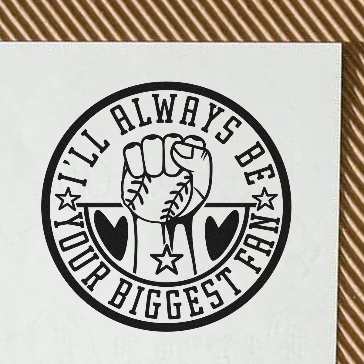 Black circular stamp seal with raised fist, hearts and stars, reading Ill always be your biggest fan on white background.