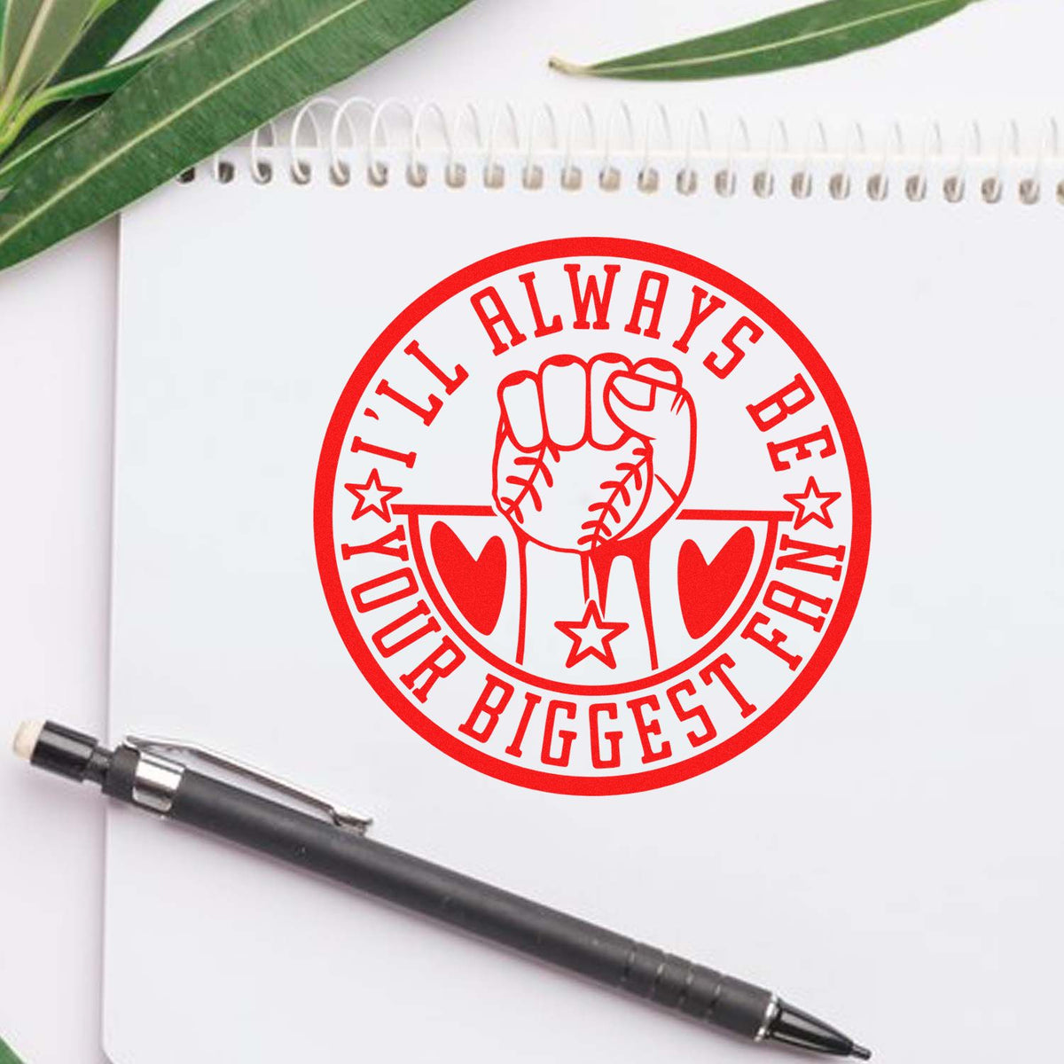 Red custom stamp seal with baseball fist and Ill always be your biggest fan on a notebook, with black pen and green leaves.