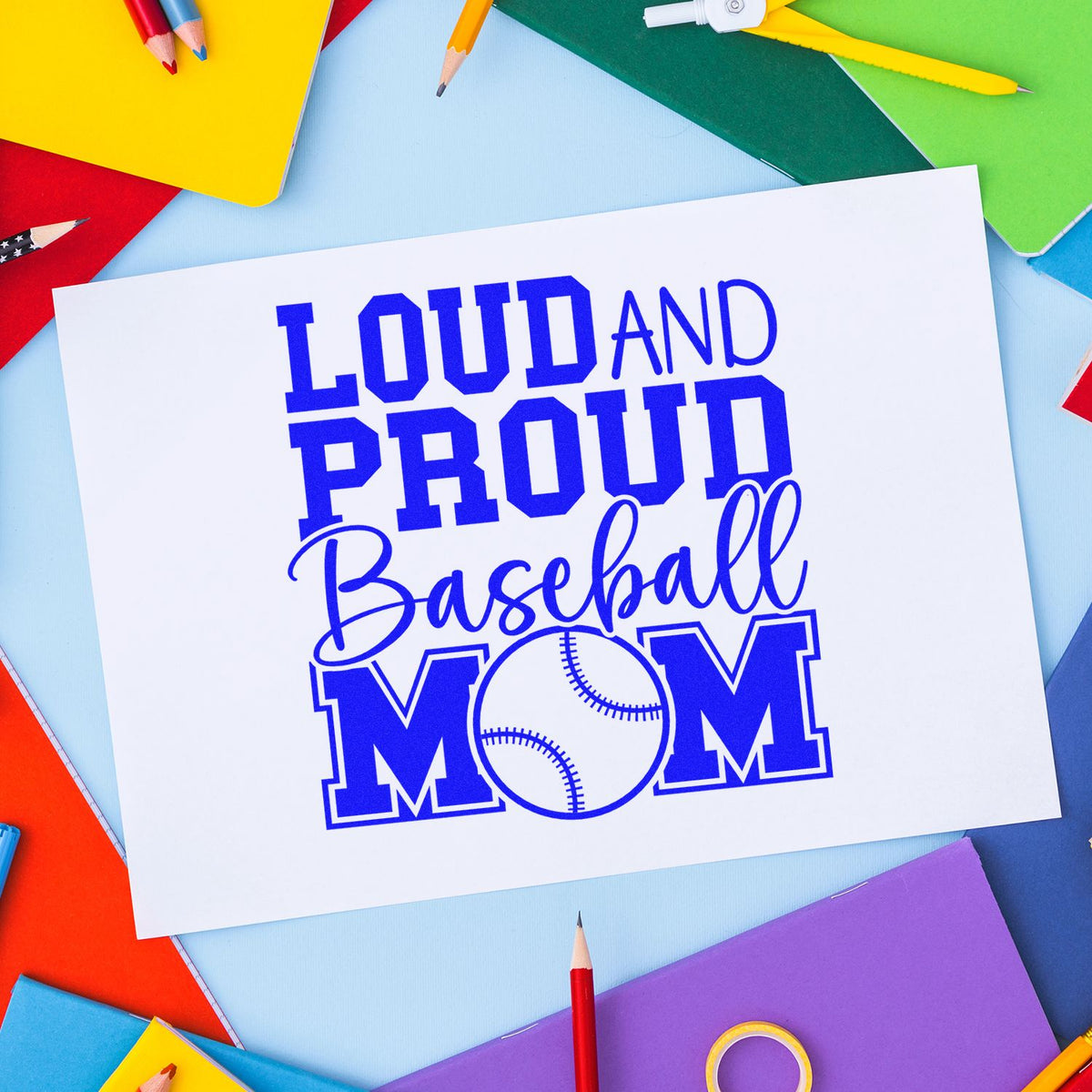 Blue Loud and Proud Baseball Mom custom stamp design on white paper, framed by colorful pencils and notebooks.