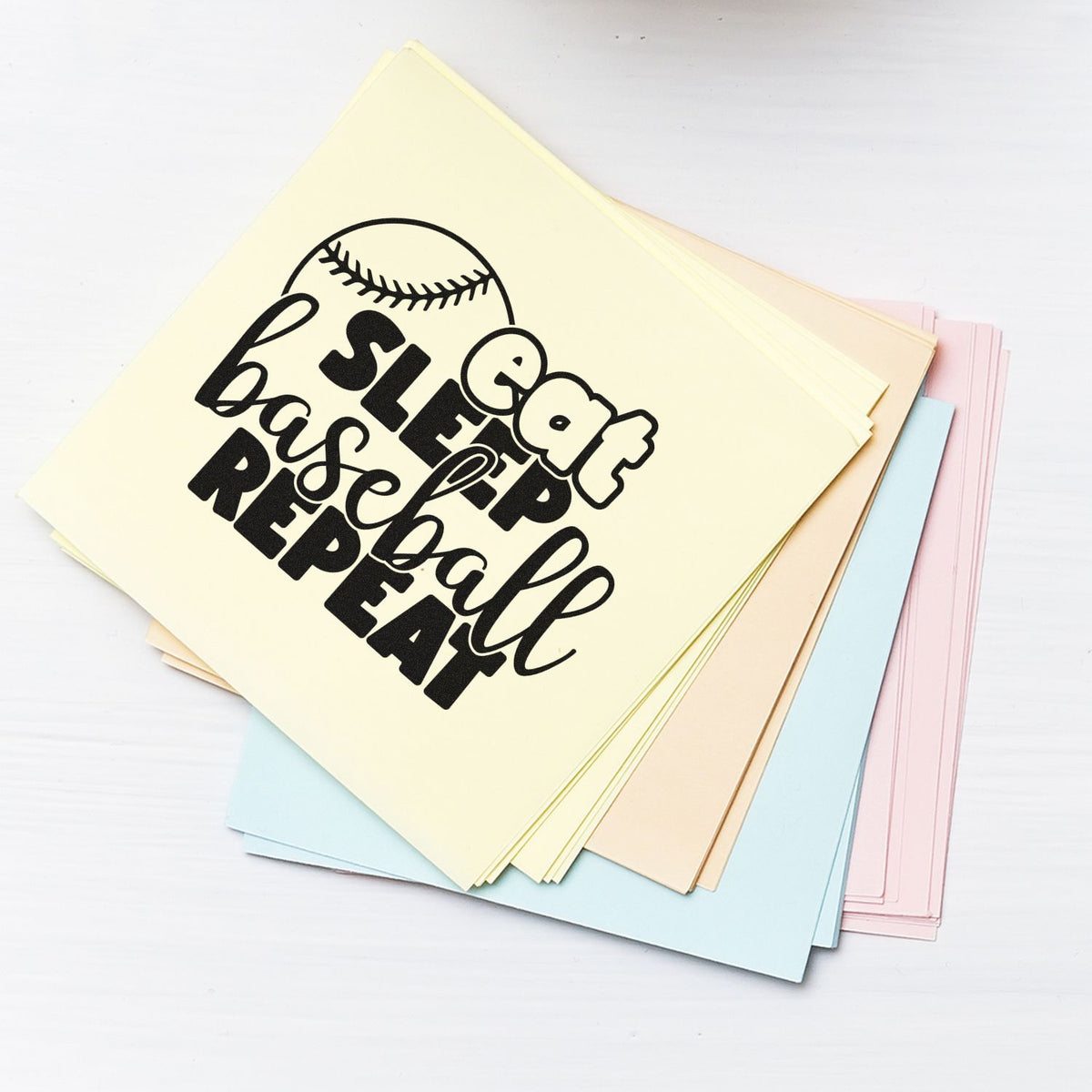 Pastel stamp and seal paper swatches with black baseball-themed eat sleep baseball repeat design on cream sheet
