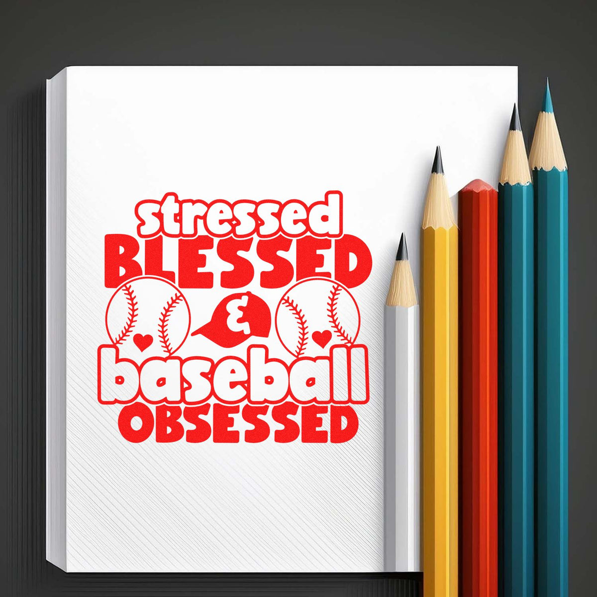 Red baseball-themed stamp and seal design reading stressed blessed baseball obsessed on white paper, beside colored pencils.