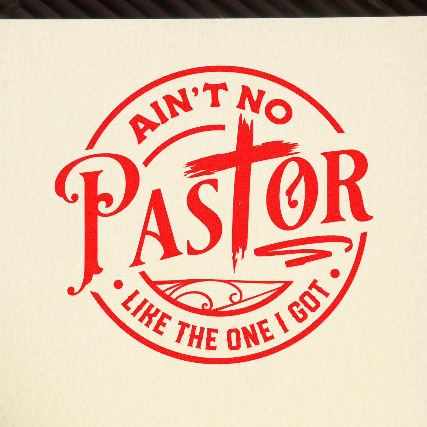 Red circular stamp seal with bold red lettering reading Aint No Pastor Like The One I Got on a cream background.