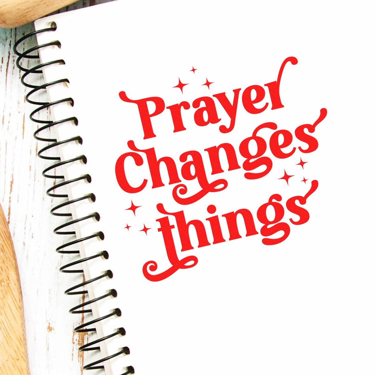 Red Prayer Changes Things stamp design on a white spiral notebook, with black coil binding and sparkles.