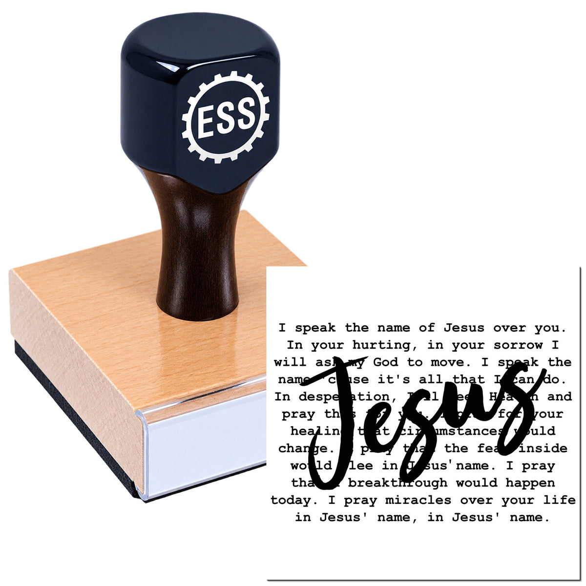 Black ESS rubber stamp seal on a wooden base, pressing "Jesus" over printed prayer text on a white background.