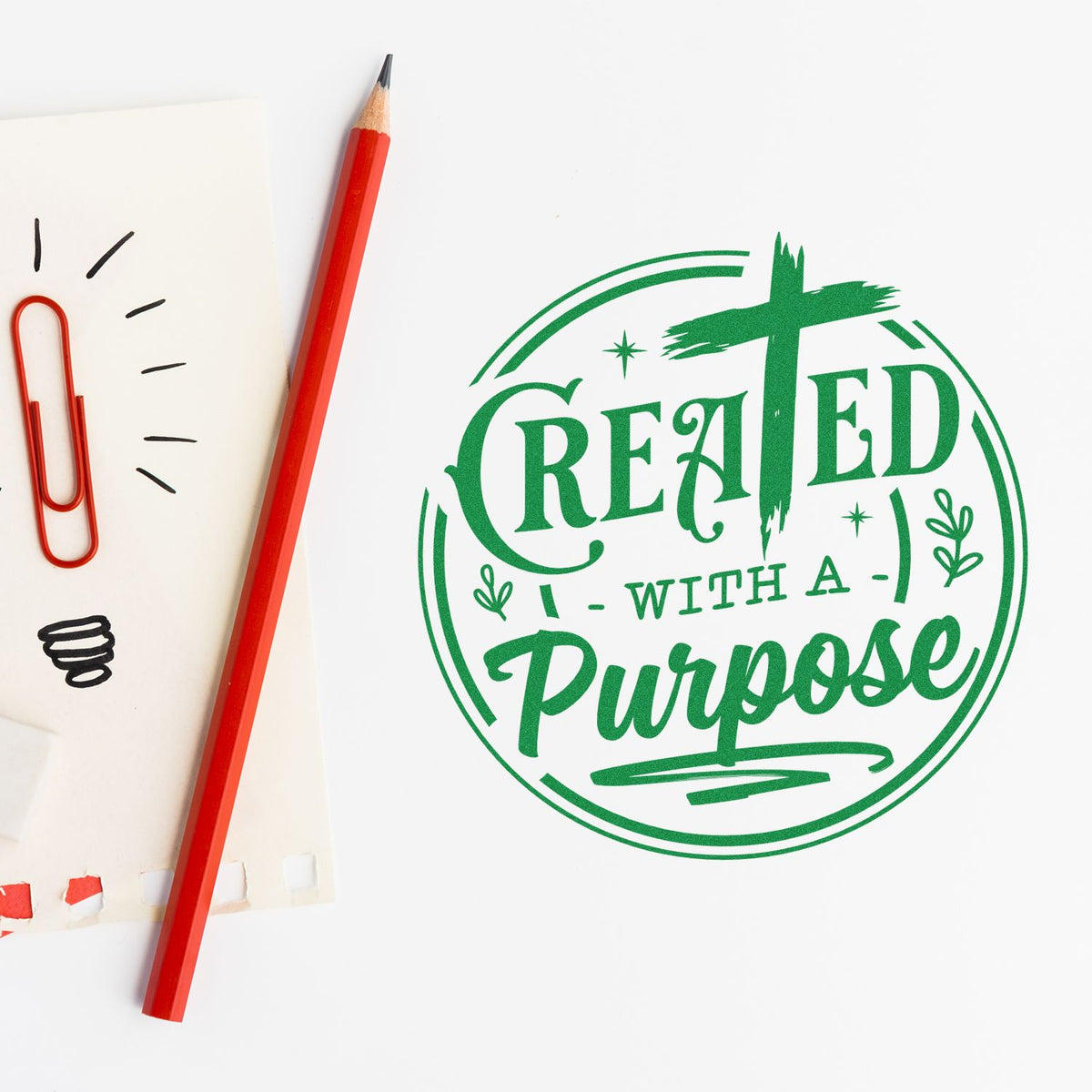 Green circular stamp seal reading Created with a Purpose beside a red pencil, paperclip, and sketch notes.