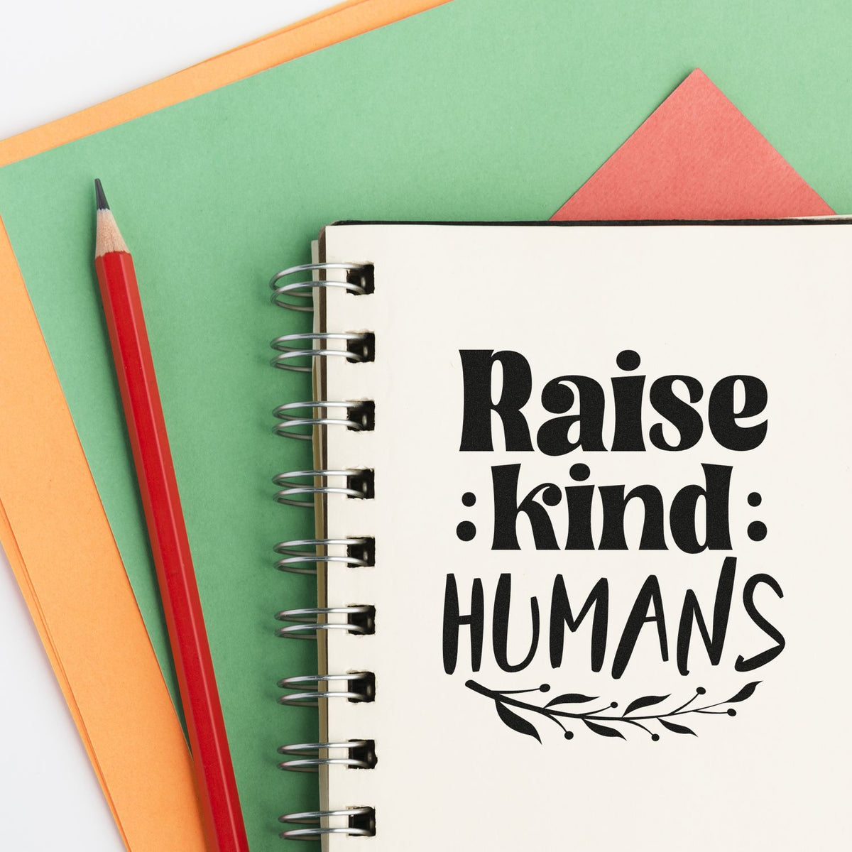 Vintage Pro Raise Kind Humans Premium Wooden Stamp imprint stamped in black ink. Bold mixed lettering reads "Raise kind humans" above a leafy branch.