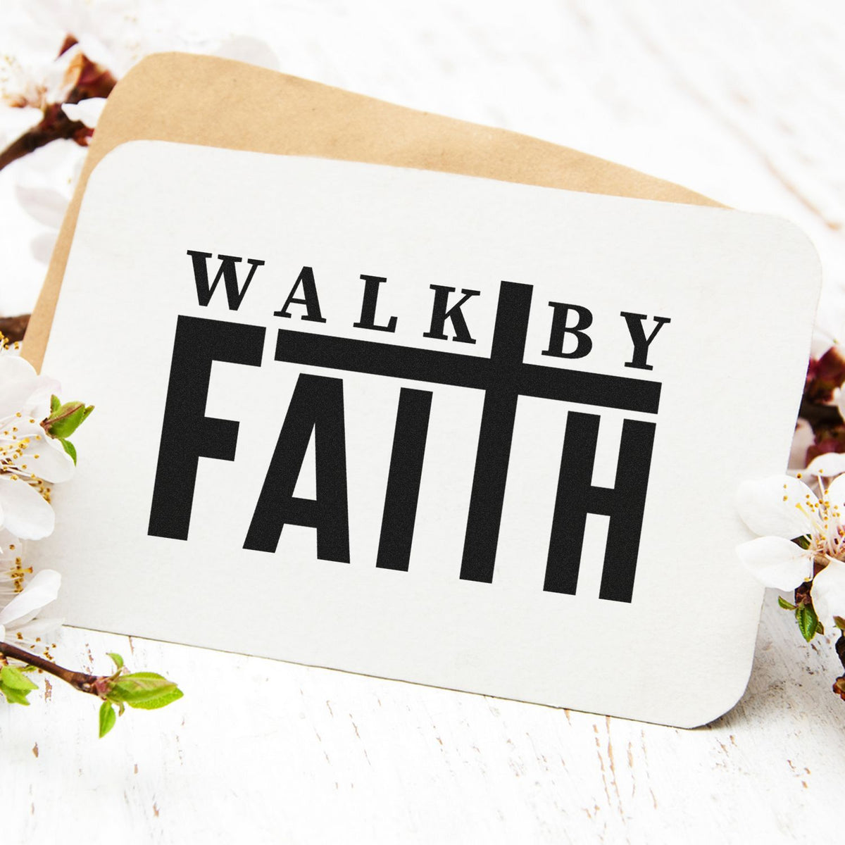 White stamp and seal card with bold black WALK BY FAITH text on a tan envelope, framed by white blossoms.