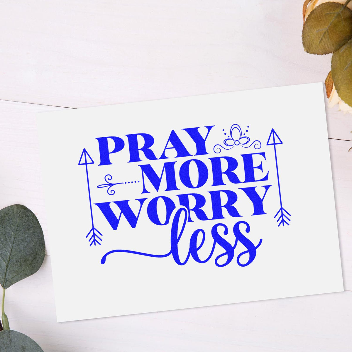 Blue Pray More Worry Less stamp and seal design on white card with decorative arrows and flourishes.