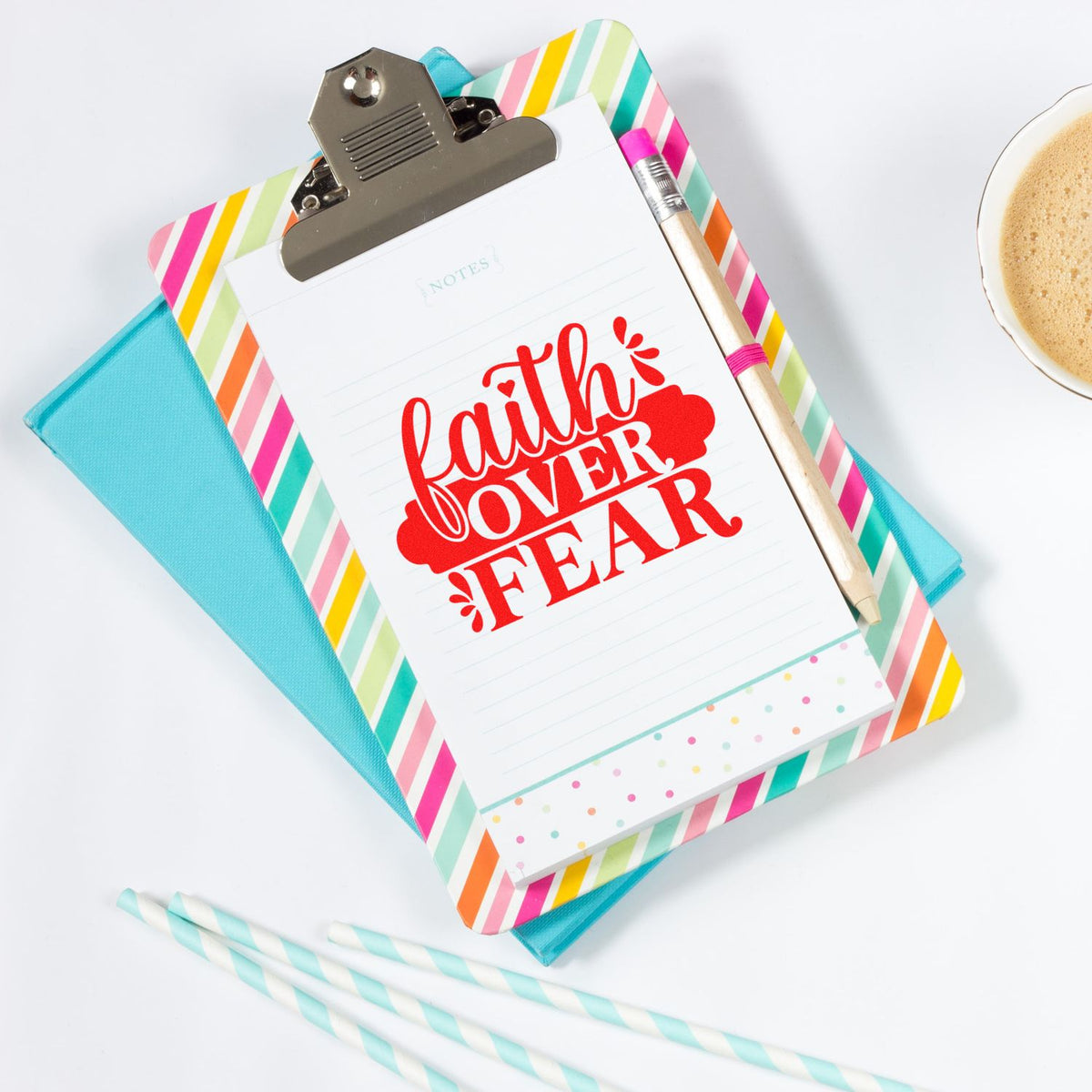 Colorful clipboard notepad with red faith over fear stamp seal, striped border, pencil, and turquoise folder