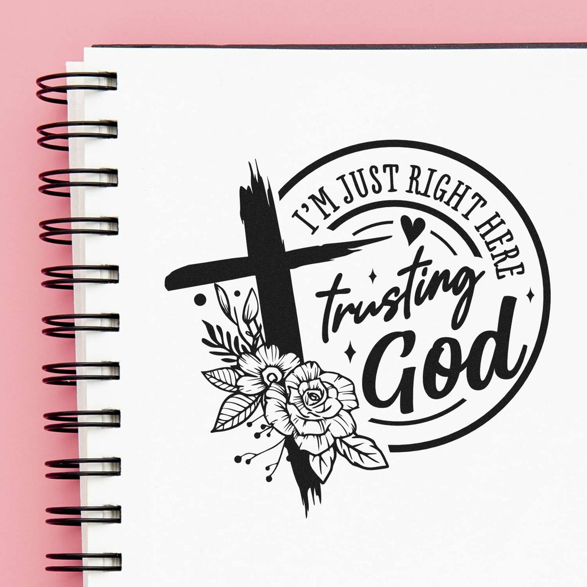 Black faith stamp and seal design on white spiral notebook, with cross, florals, and "I'm just right here trusting God" on pink background.