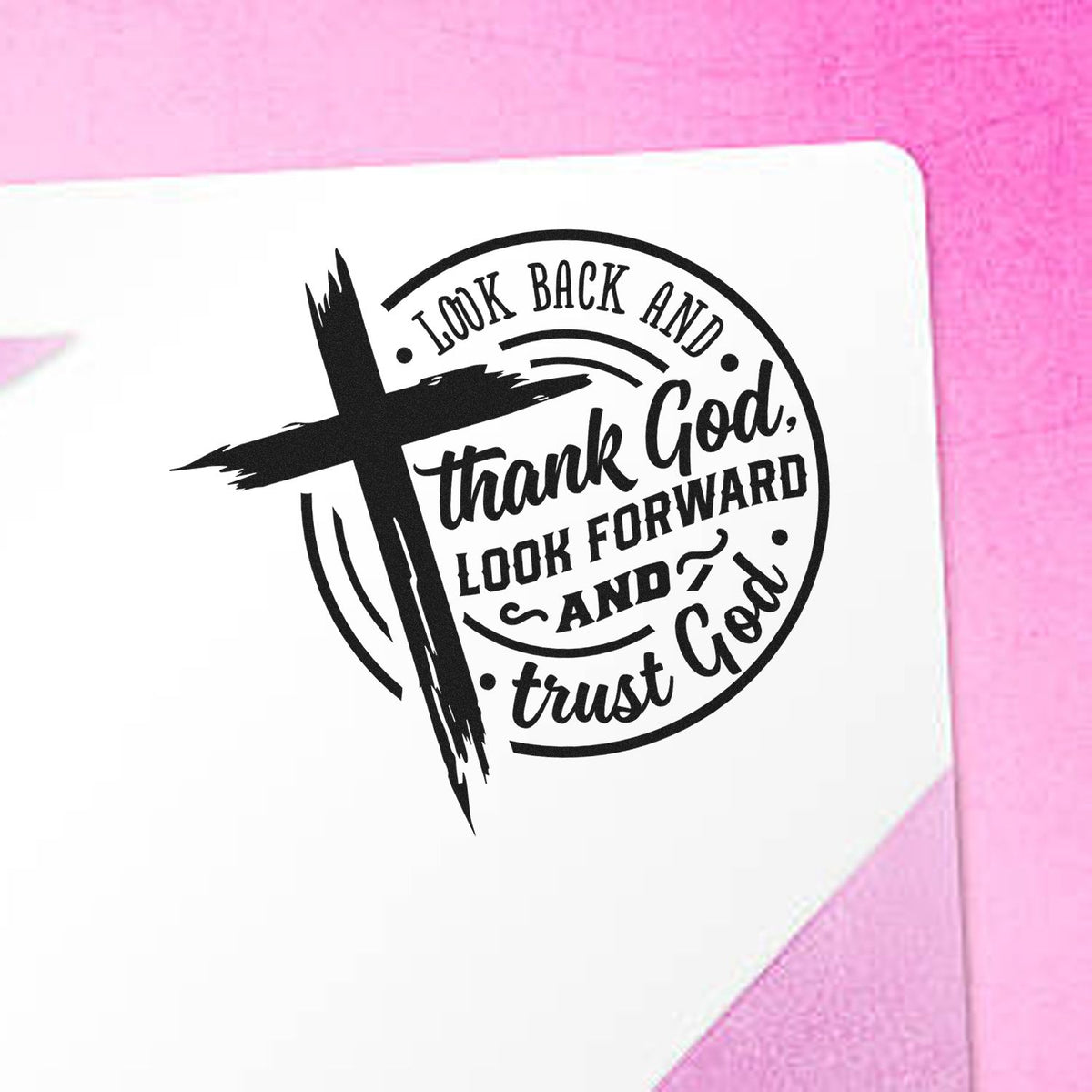 Look Back Thank God Badge Slim Pre-Inked Stamp imprint stamped in black ink. A brushstroke cross overlaps a circular "Look back and thank God, look forward and trust God" design.