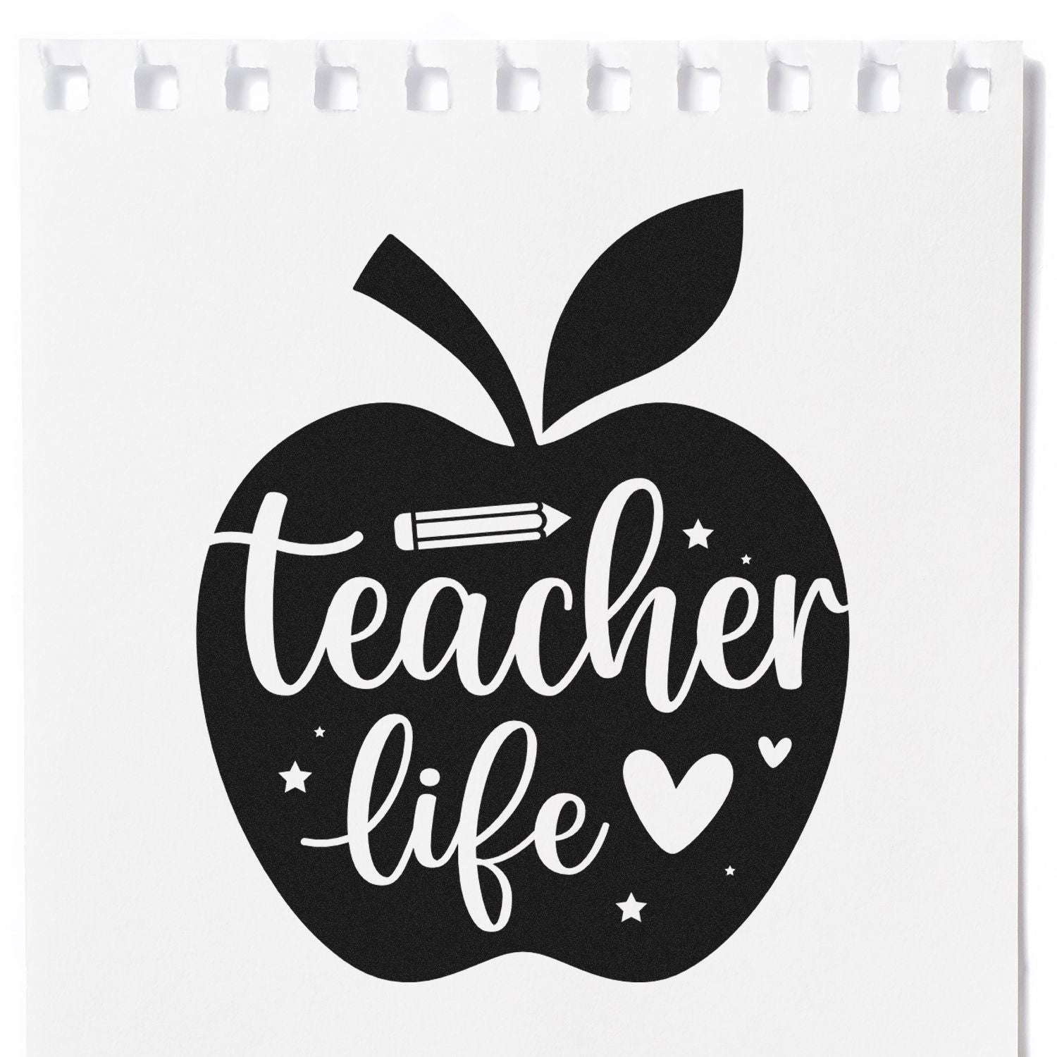 Black teacher life apple stamp seal with white script, pencil, stars and heart on a white notebook page.