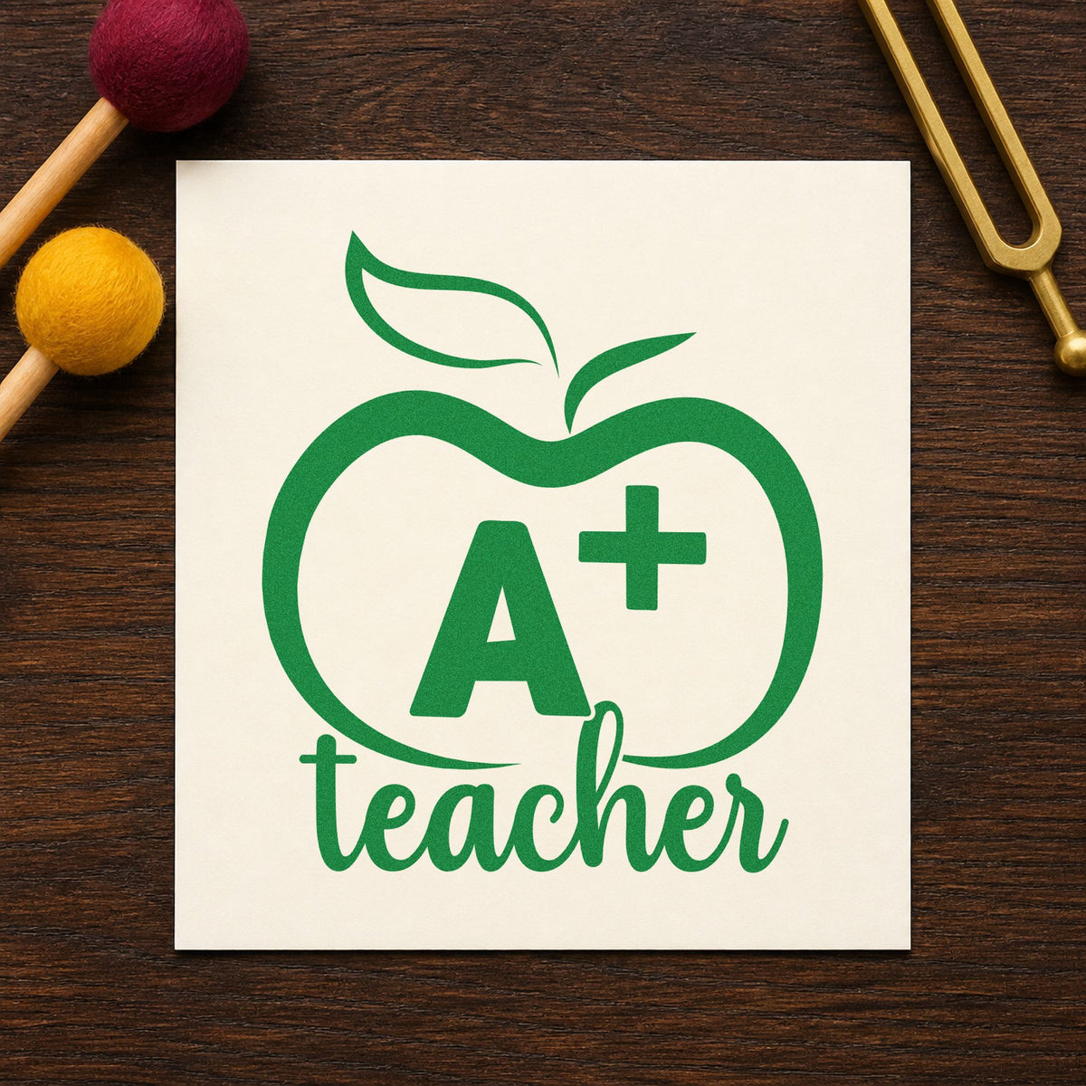 A Plus Teacher Outline Apple craft stamp imprint in green ink on a handmade project, one idea being framed honors board.